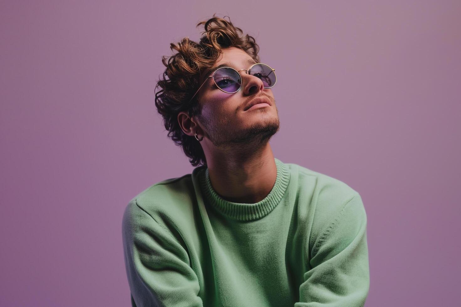 Chic male fashion model in a green pullover with eyewear against a soft lilac background highlighting casual fashion and relaxed lifestyle portrait photo