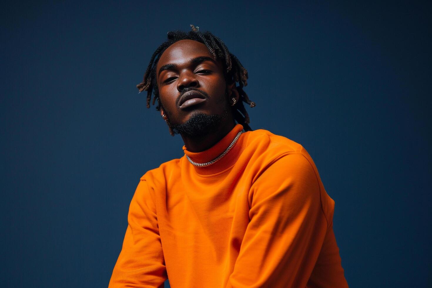 Bright Orange pullover Clad Male with Navy Blue Background Focusing on Trendy Fashion in a Stylish Lifestyle portrait photo