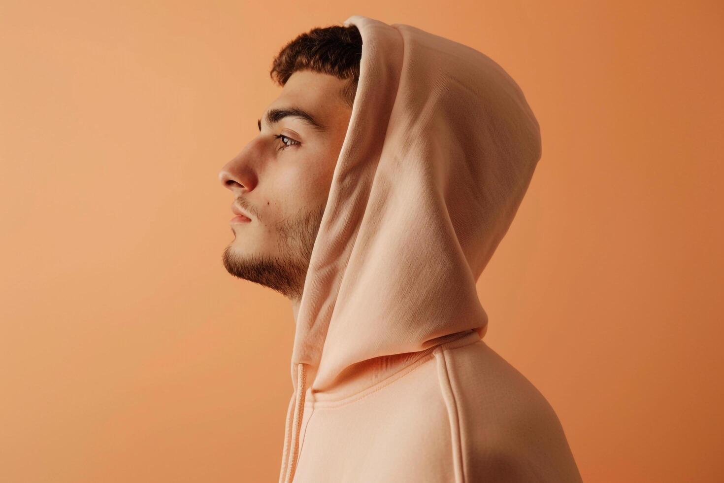 Hoodie Clad Male with Soft peach Background Lifestyle portrait Highlighting Cozy Costume Style and Gentle Casual Fashion photo