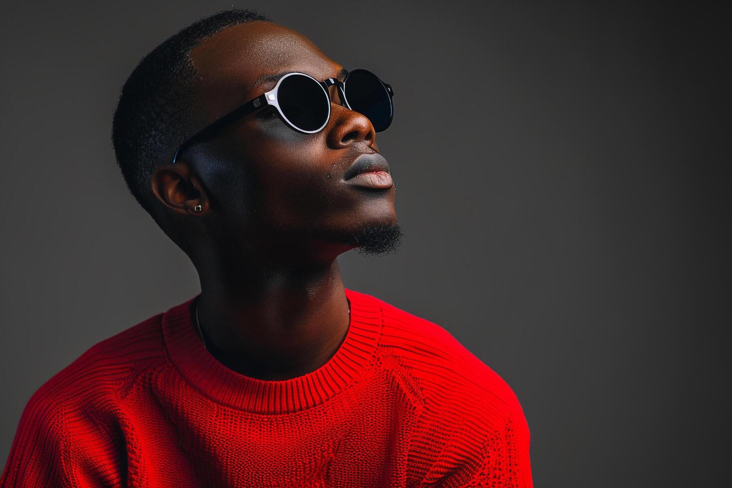 Red pullover and Sunglasses on Male with Charcoal Background  Fashion portrait emphasizing Bold Style and Lifestyle Trends photo