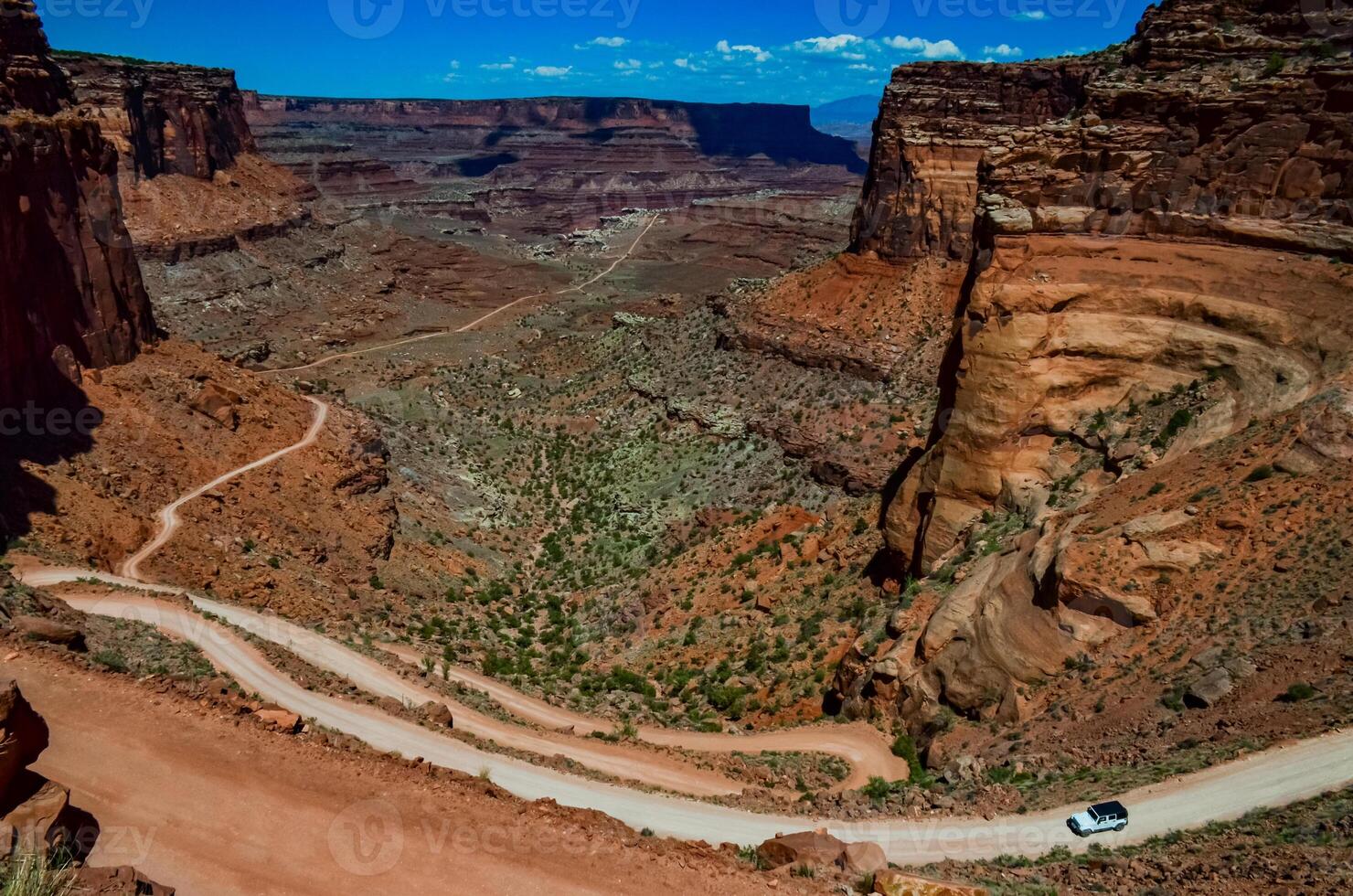 Dirt road at the bottom of the canyon among the layered geological formations of red rocks. photo