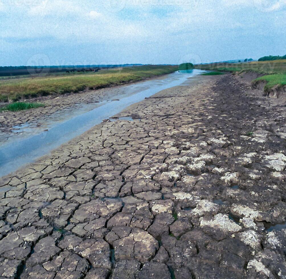 Cracked earth, drying up small river in the steppe zone in southern Ukraine photo