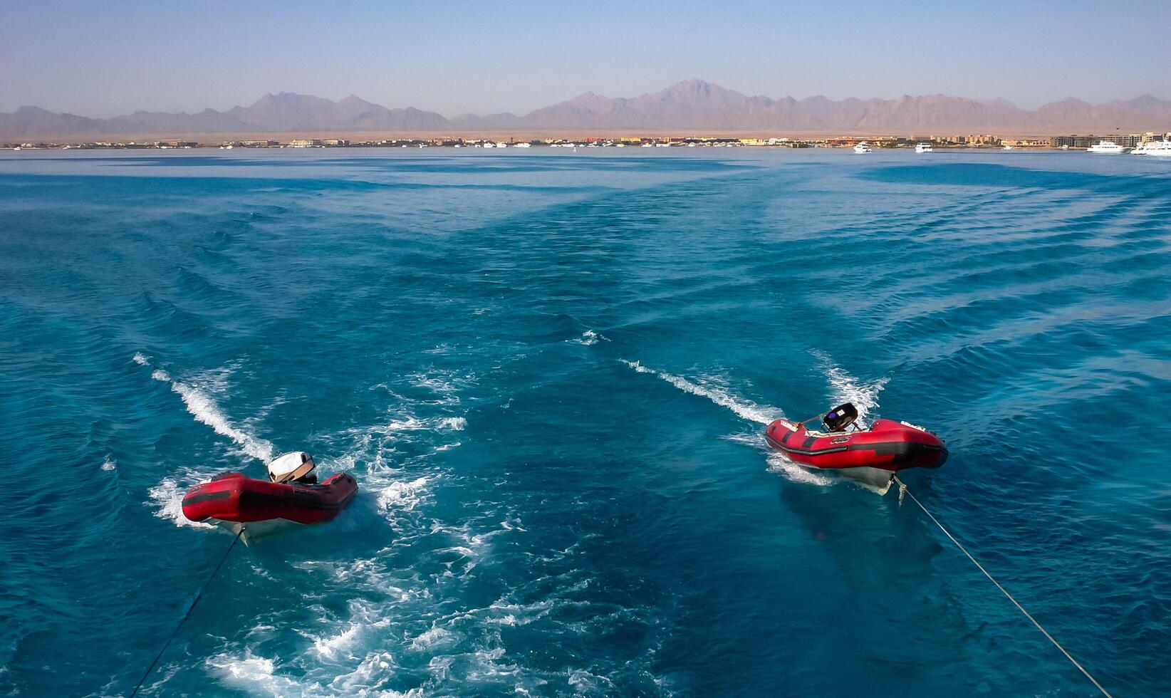 Hurhgada, Egypt - April 9, 2006 Inflatable rubber boats are pulled by a yacht on ropes in the Red Sea photo