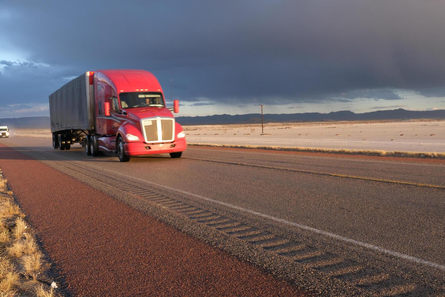red truck on a flat asphalt road passing through the desert in Arizona, USA photo
