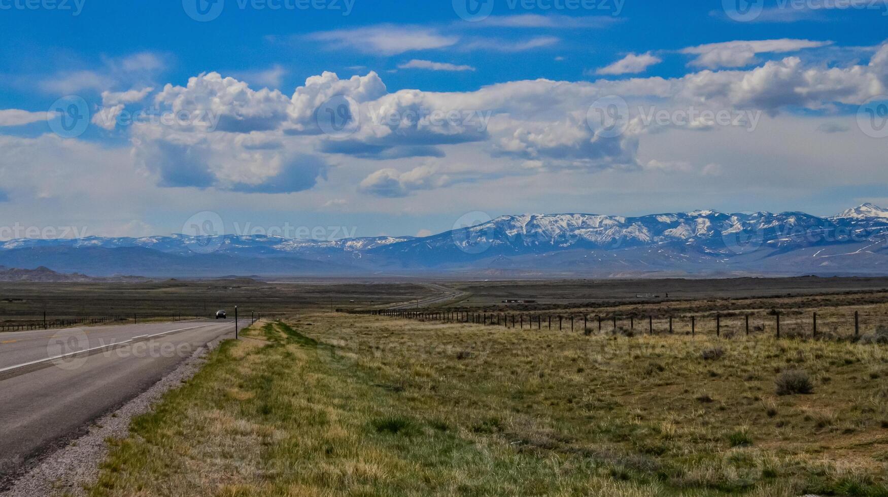 The landscape is in the wild. A road going into the distance, white clouds on the horizon. photo