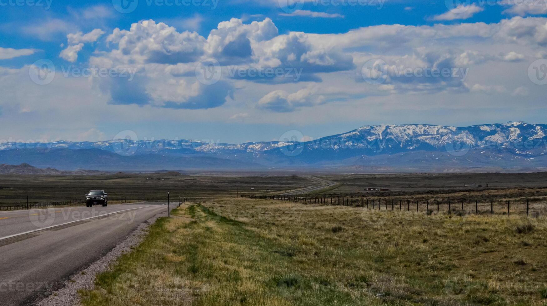 The landscape is in the wild. A road going into the distance, white clouds on the horizon. photo
