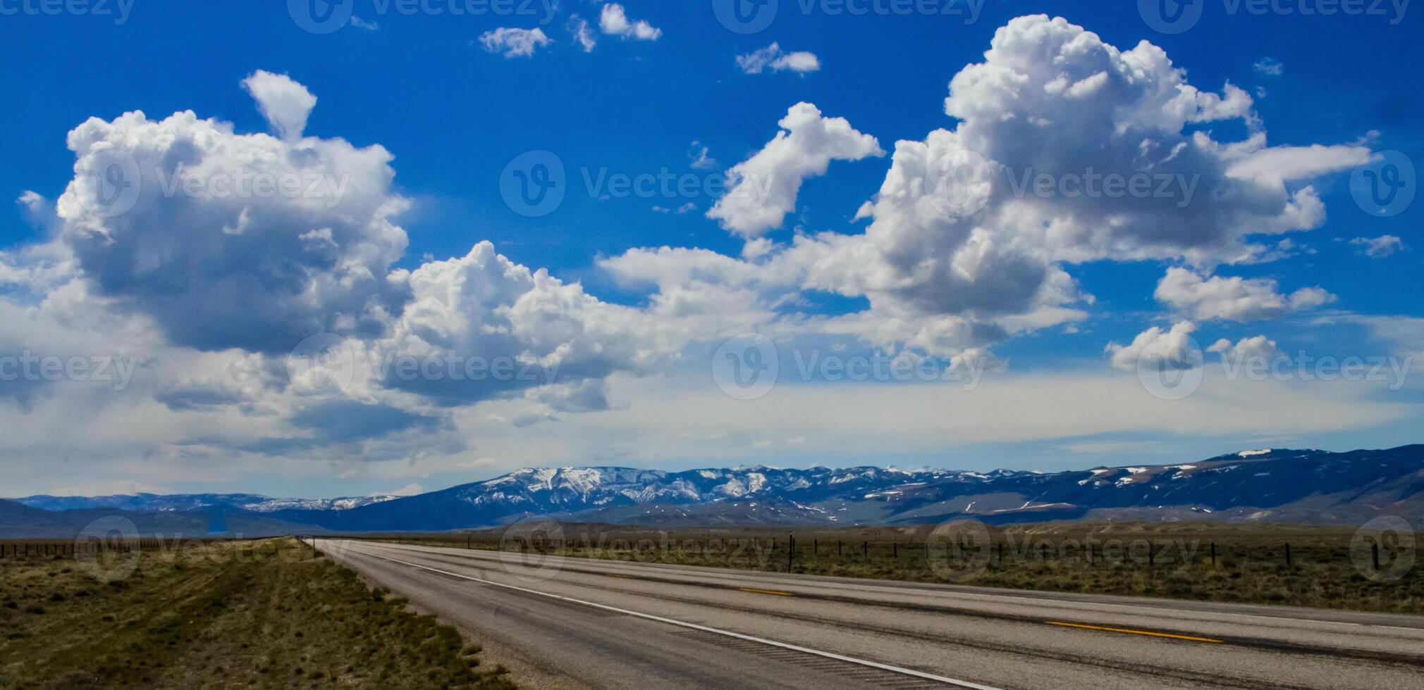 The landscape is in the wild. A road going into the distance, white clouds on the horizon. photo