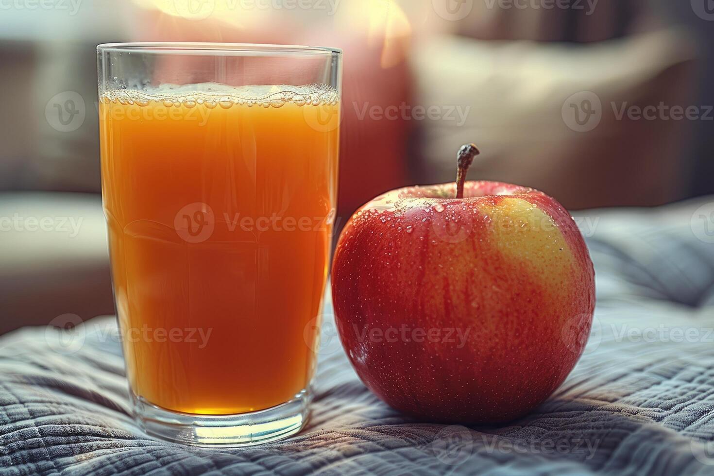 A Glass of Apple Juice and a Fresh Red Apple on a Fabric Surface photo