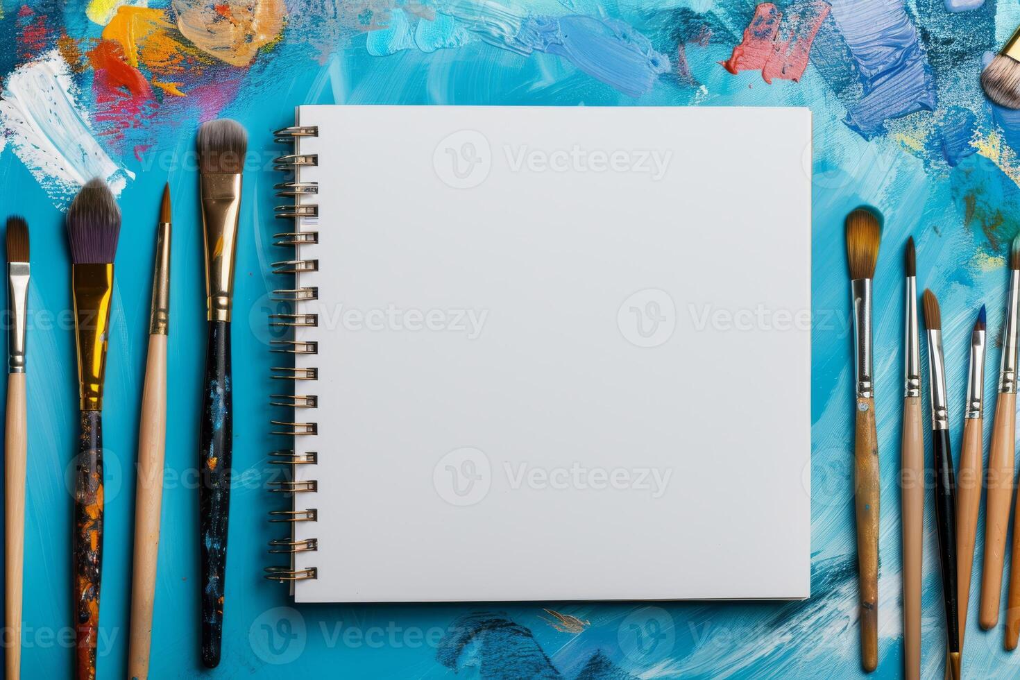In a vibrant art scene, a pristine blank sketchpad takes center stage, encircled by a diverse array of paintbrushes, all set against a dynamic and colorful background that inspires creativity photo