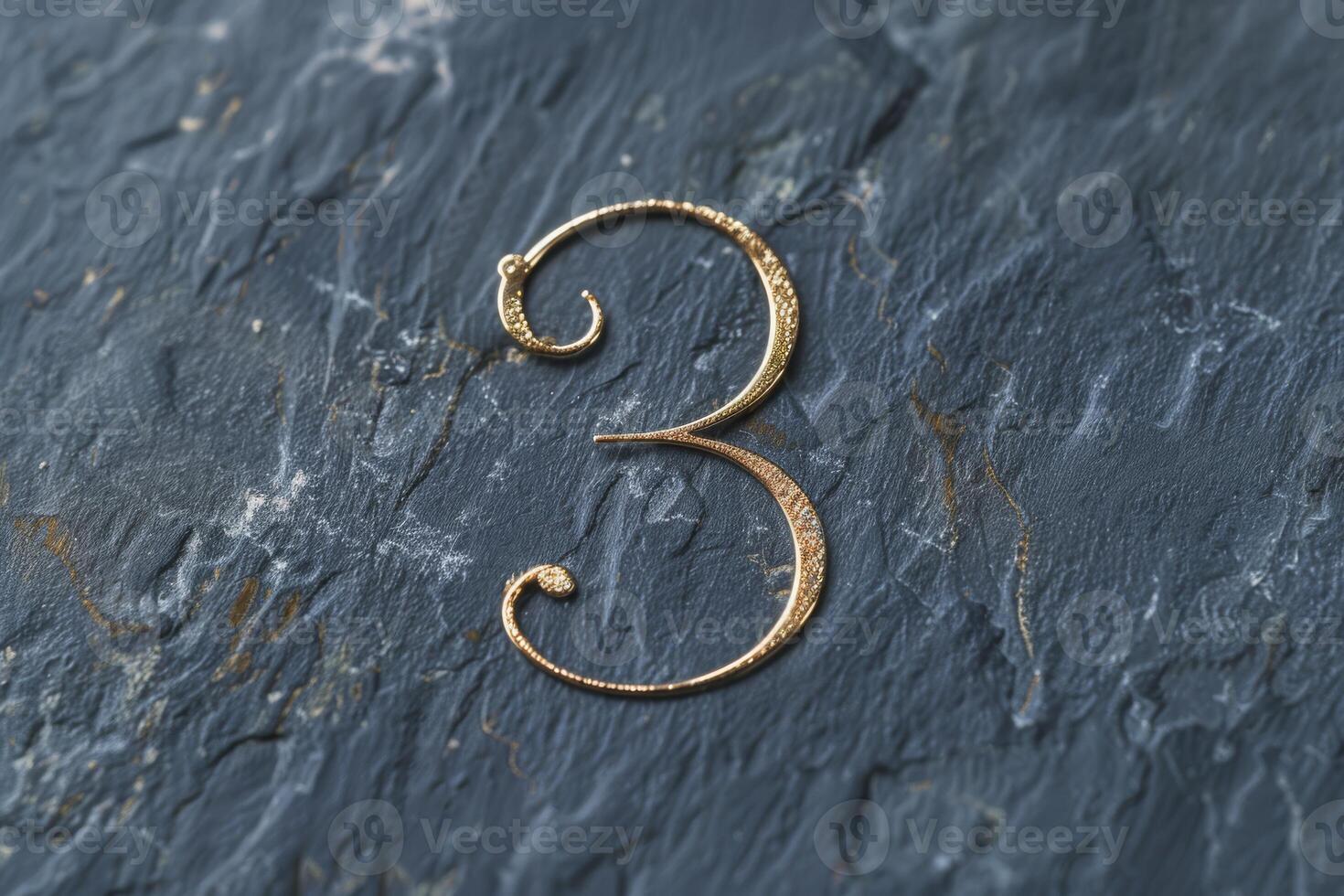 A stylish and elegant gold numeral three beautifully contrasted against a rich textured dark slate backdrop photo