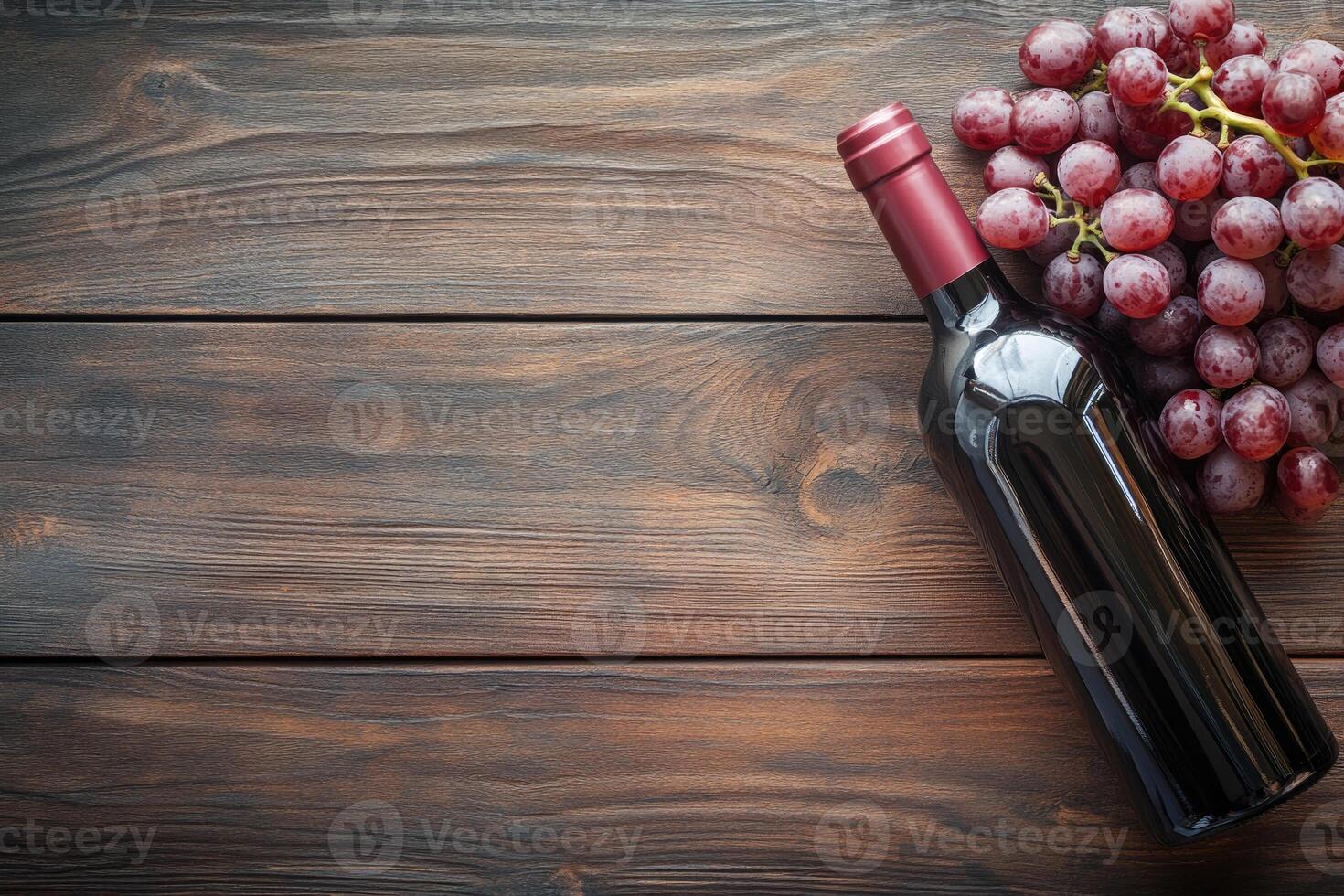A wine bottle and grapes on a wooden table with a blank area. photo