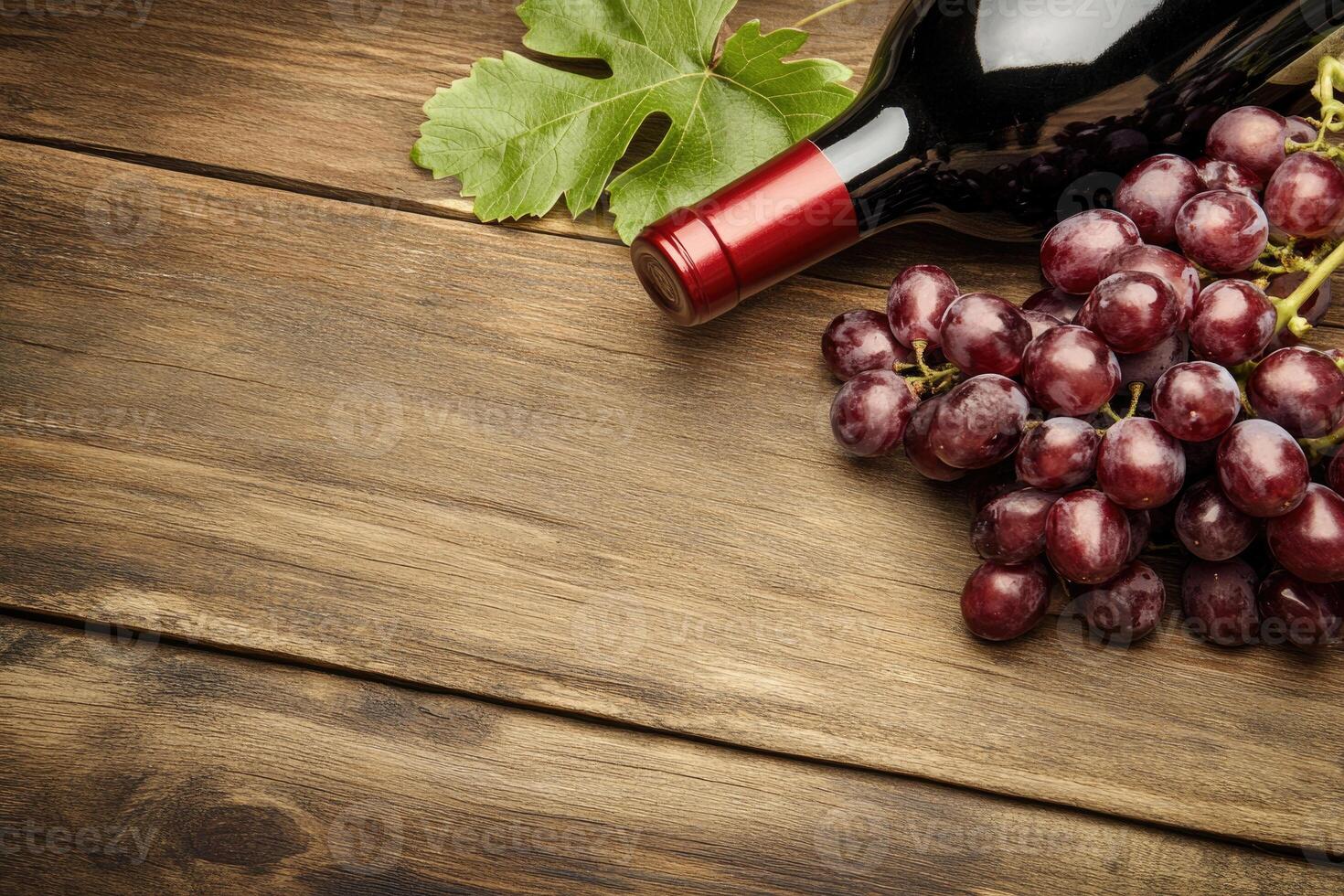 A wine bottle and grapes on a wooden table with a blank area. photo