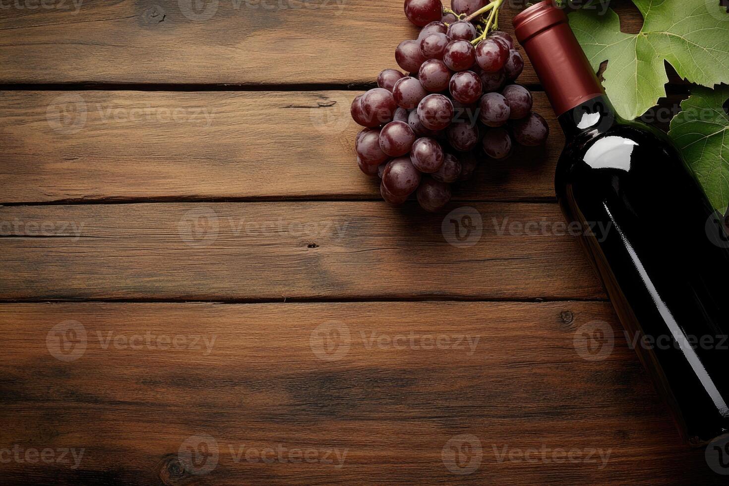 A wine bottle and grapes on a wooden table with a blank area. photo