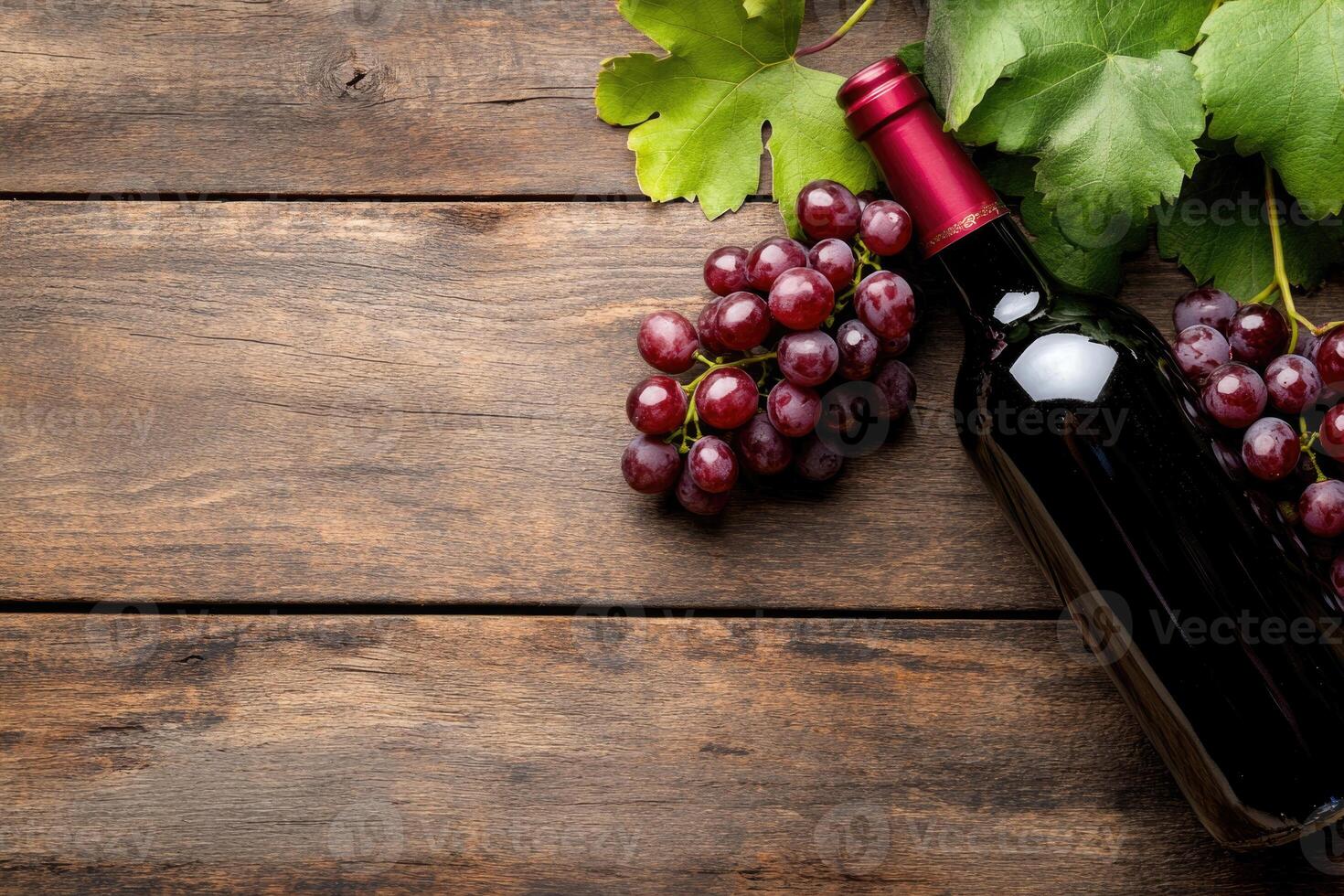 A wine bottle and grapes on a wooden table with a blank area. photo