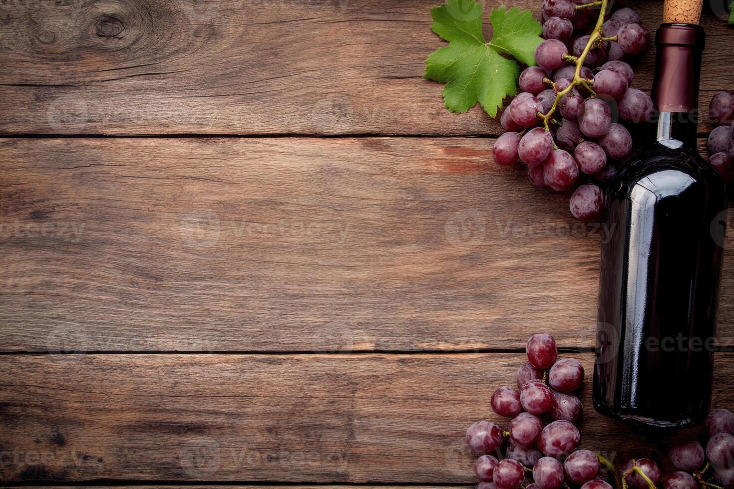 A wine bottle and grapes on a wooden table with a blank area. photo