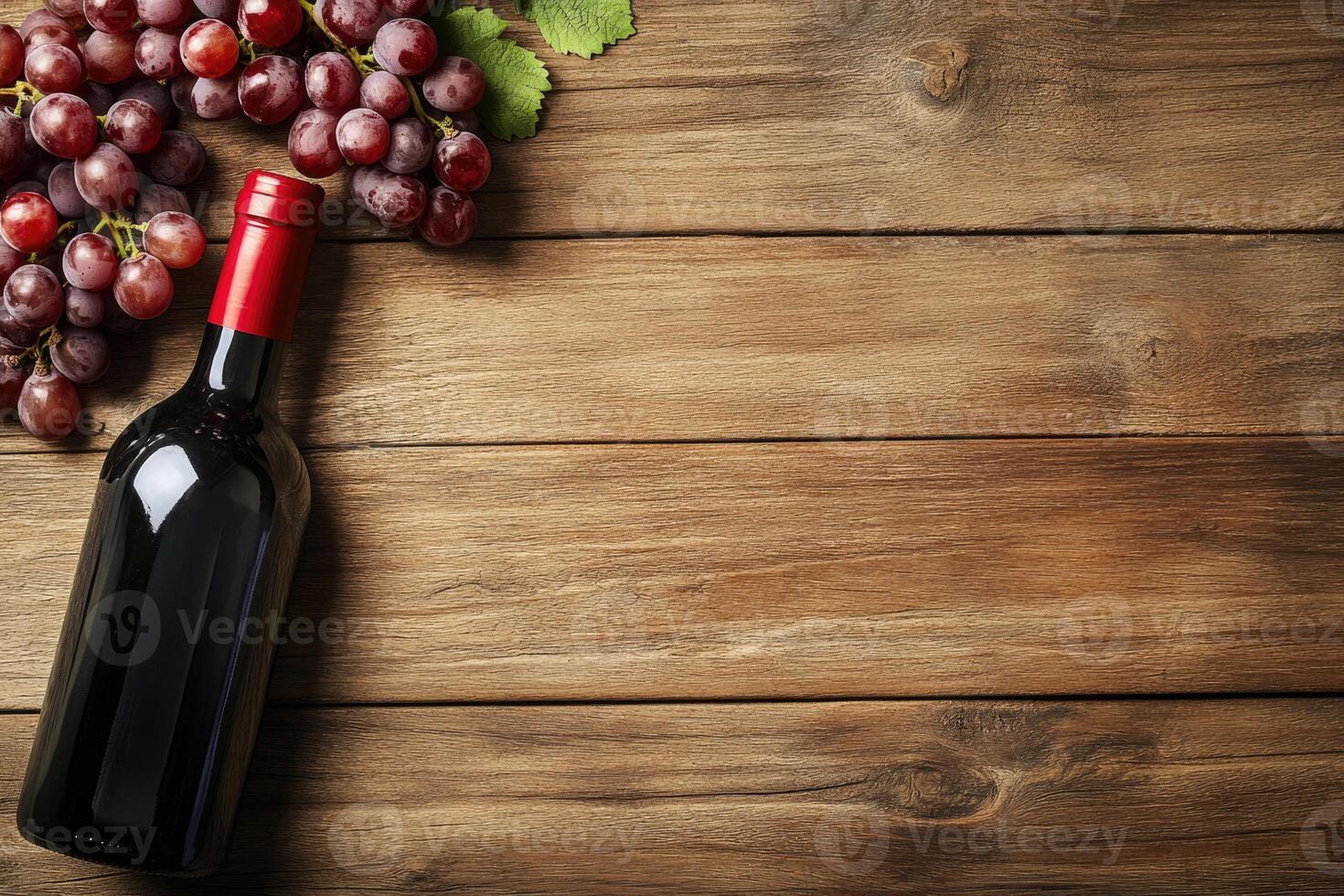 A wine bottle and grapes on a wooden table with a blank area. photo