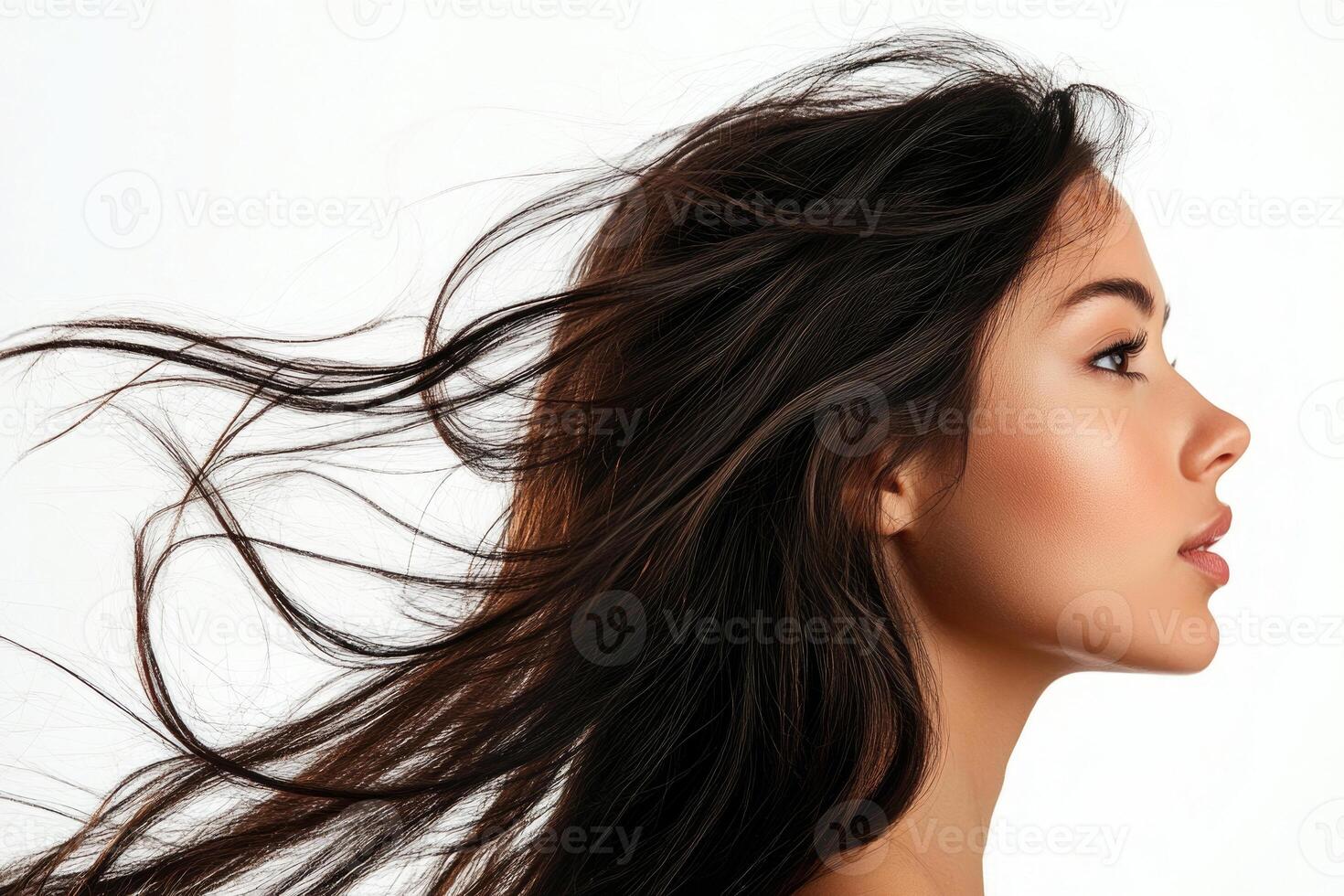 A profile portrait of a young brunette woman with flowing hair on a white background. photo