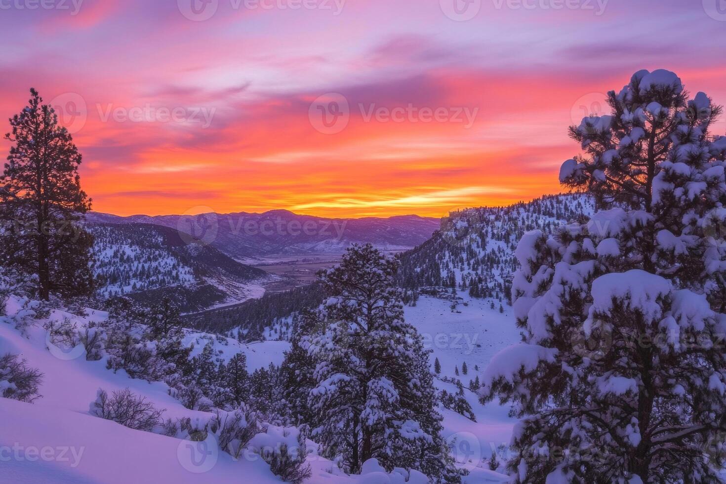 Snow-covered hills and pine trees under a vibrant sunset. photo