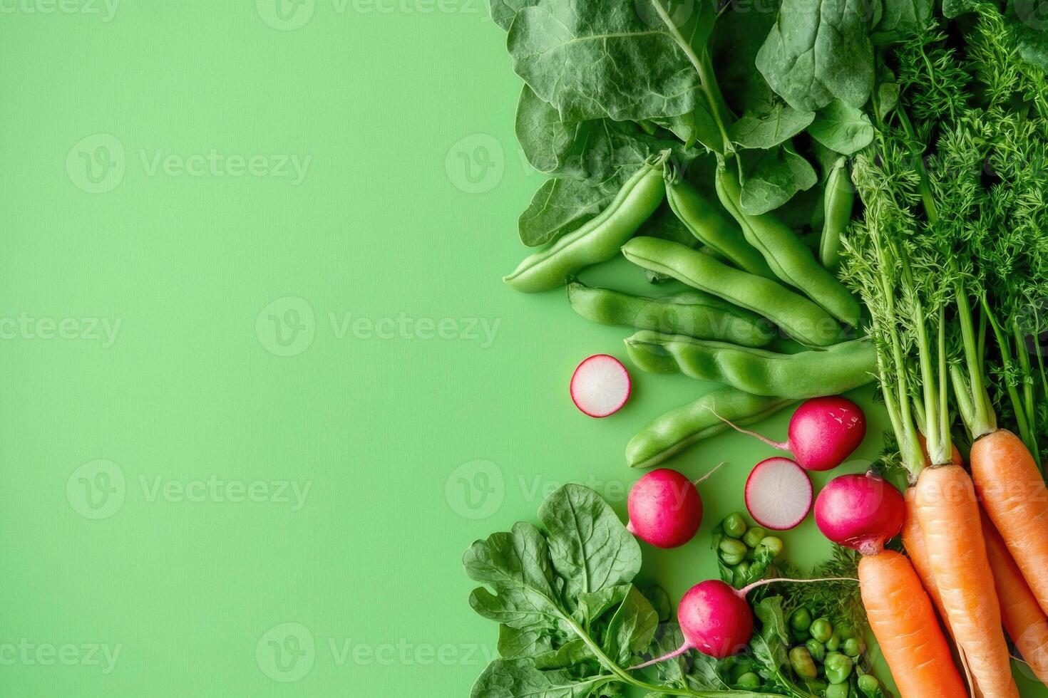 A selection of fresh spring vegetables on a bright green background. photo