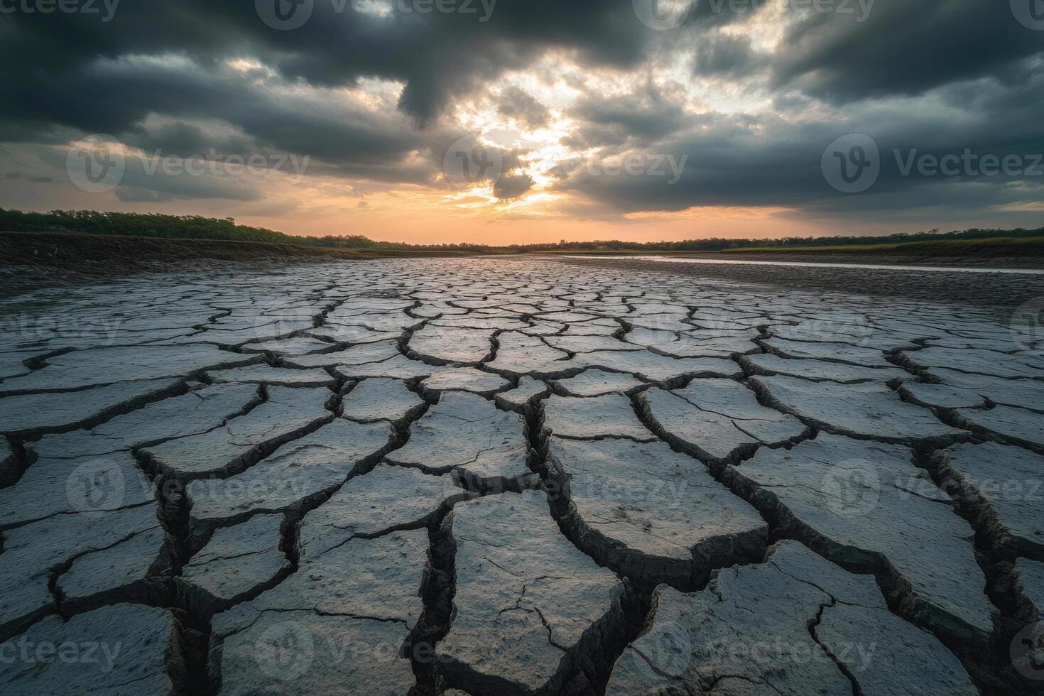A cracked, dry riverbed under a cloudy sky, symbolizing drought and thirst. photo