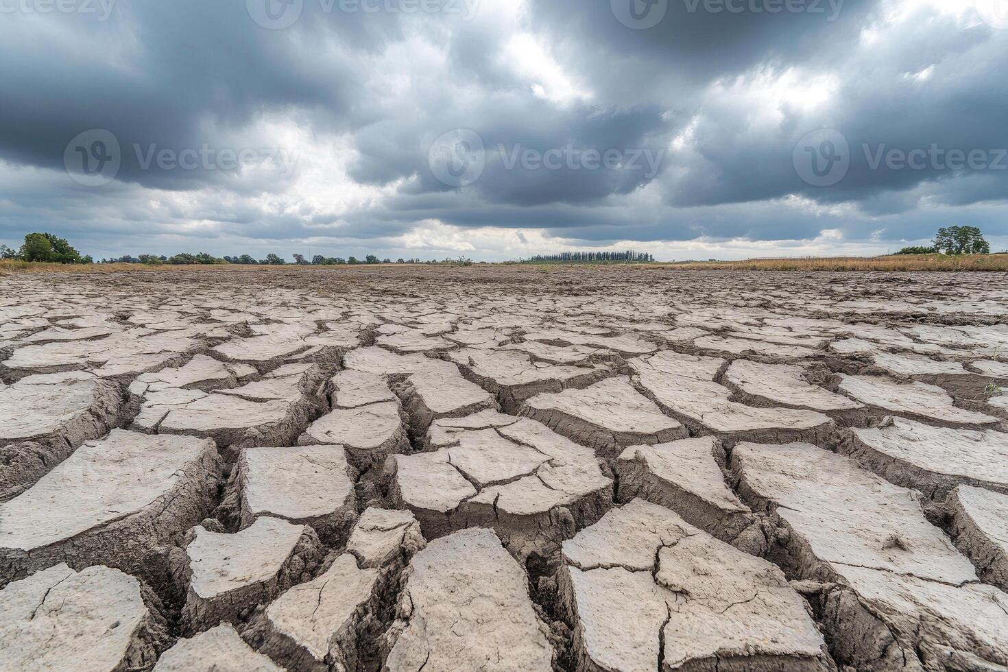 A cracked, dry riverbed under a cloudy sky, symbolizing drought and thirst. photo