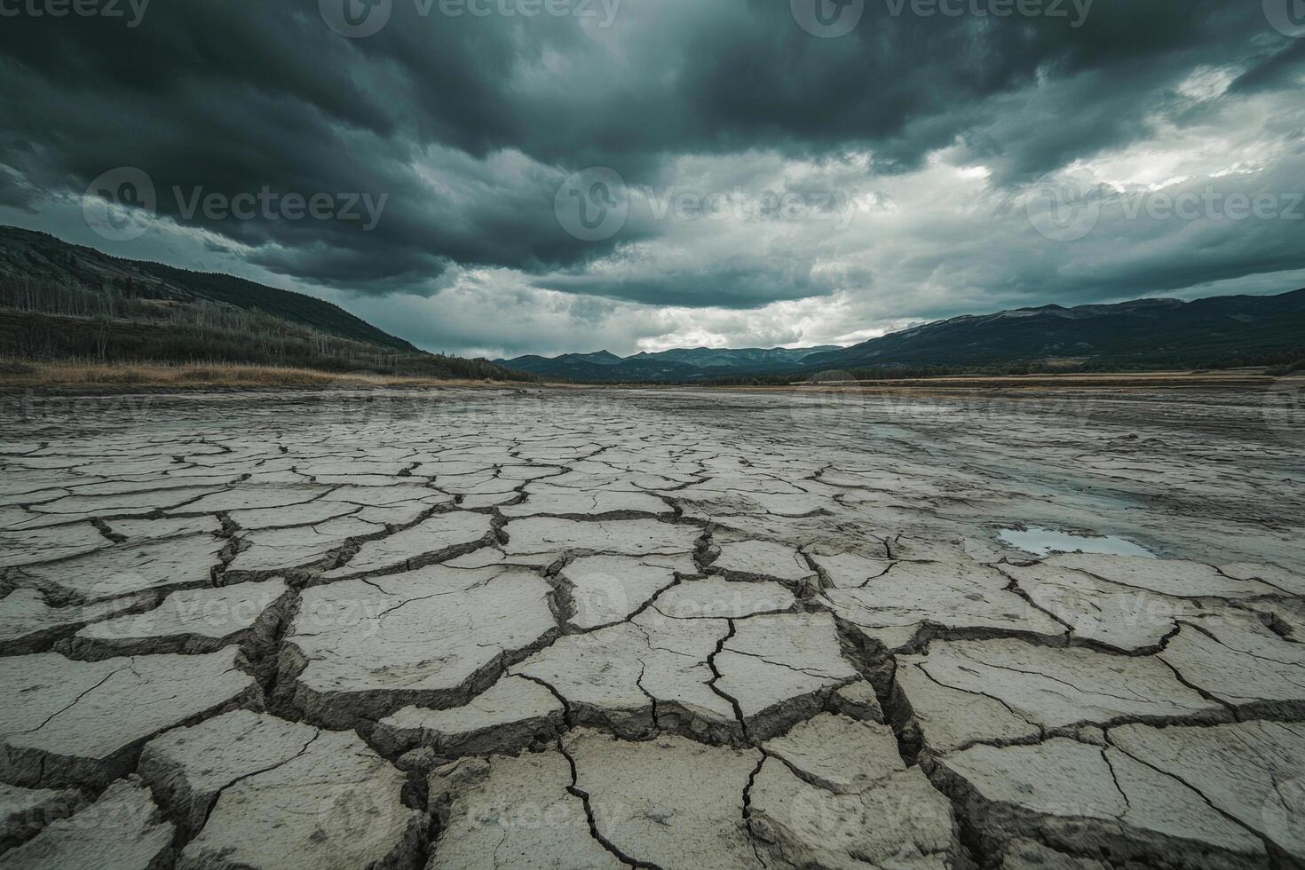 A cracked, dry riverbed under a cloudy sky, symbolizing drought and thirst. photo