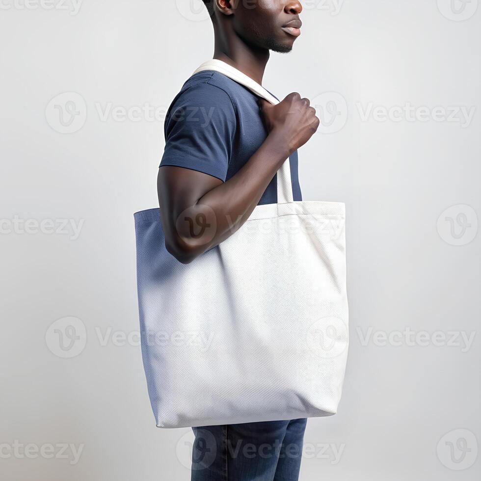 Tote bag mockup. Young African American man carrying reusable cotton linen eco organic fabric canvas blank totebag on white background. photo