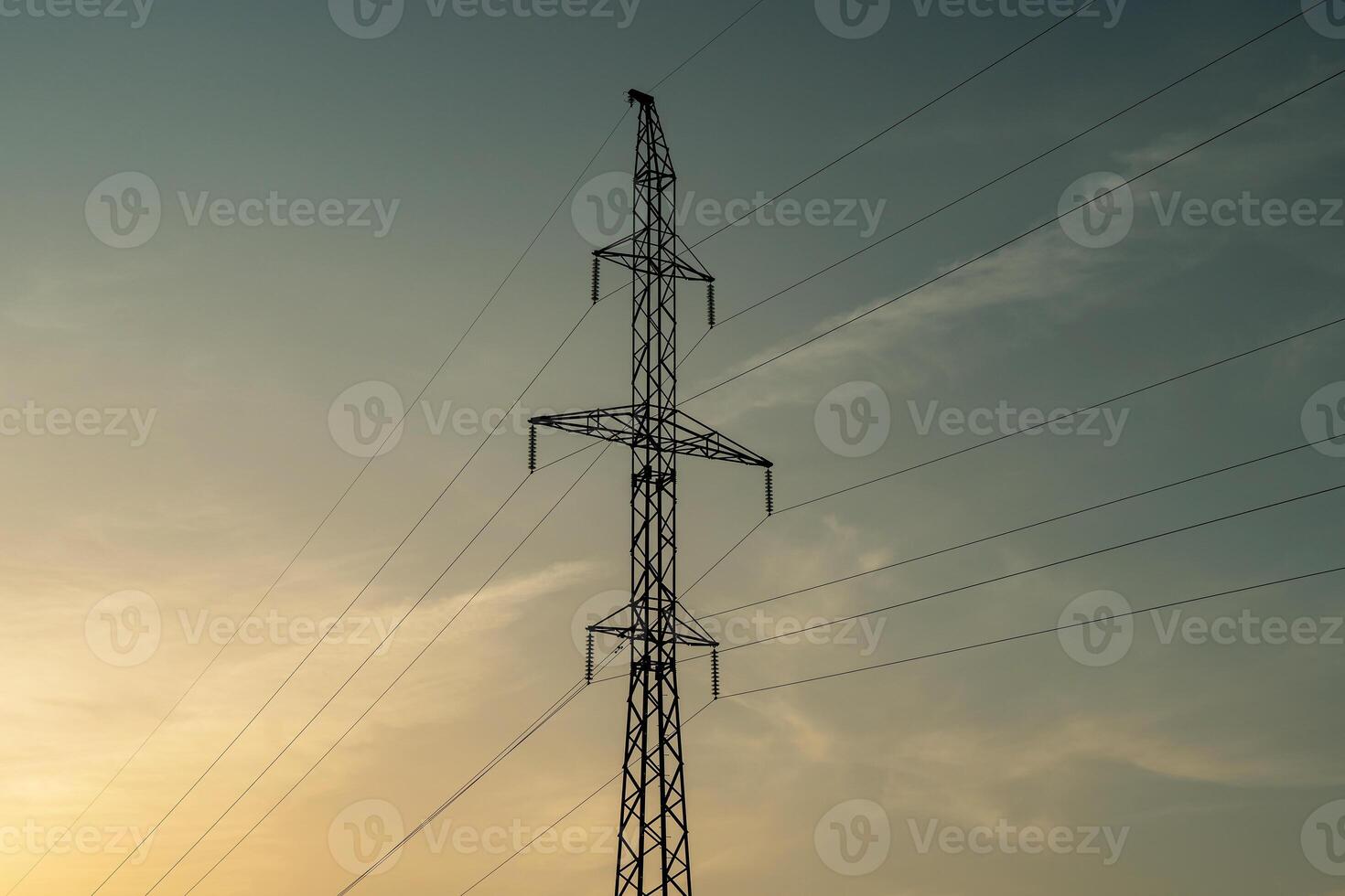 High voltage pole and wires against blue sky and setting sun. photo