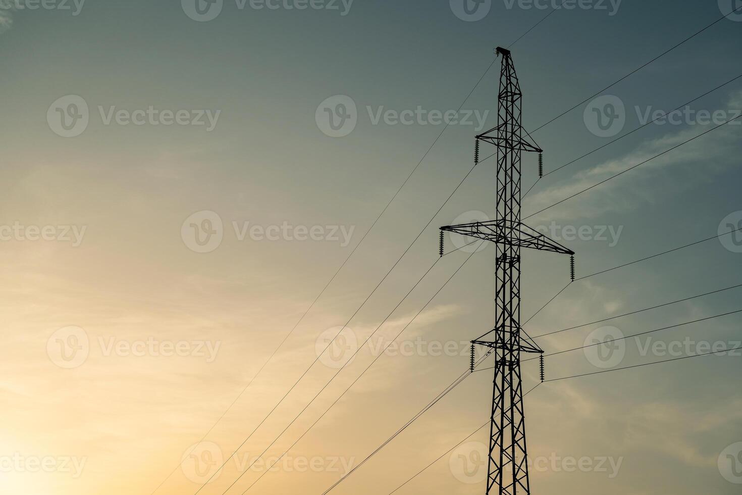 High voltage pole and wires against blue sky and setting sun. photo