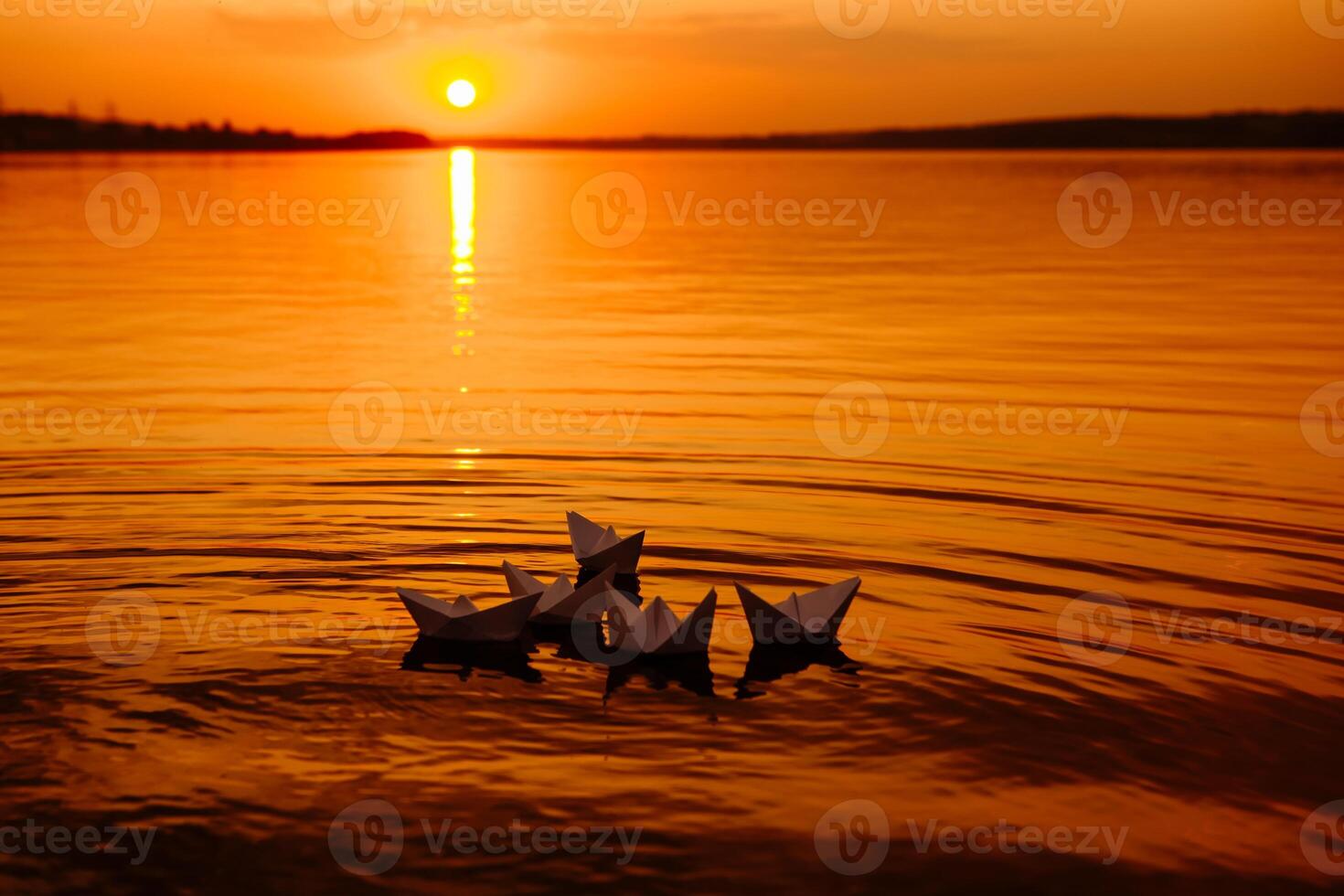 A paper boat floating away into the distance. Boat on the water. Beautiful sunset. Origami. River. Lake. photo