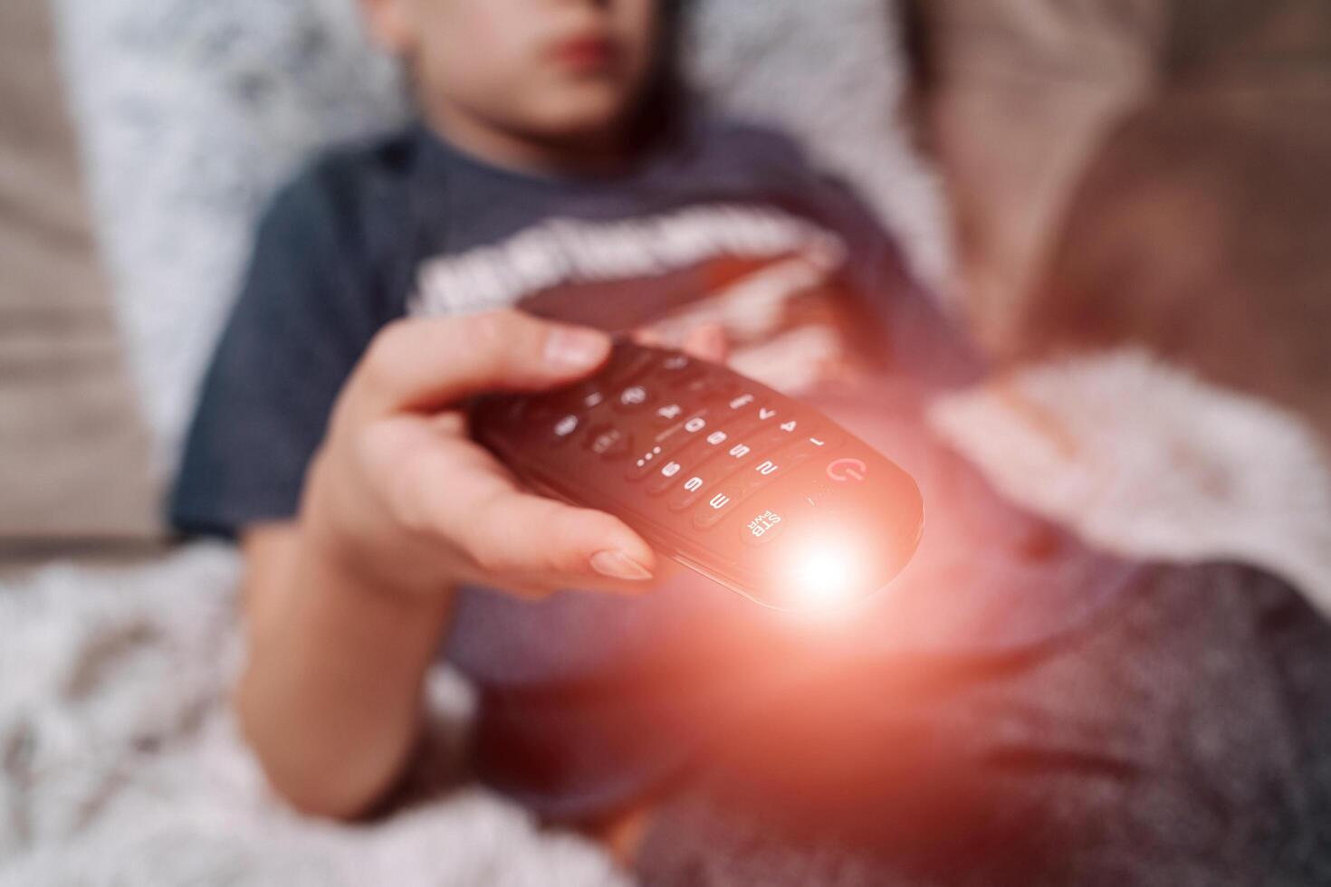 Watching TV and using remote controller. Teenage boy watching TV photo