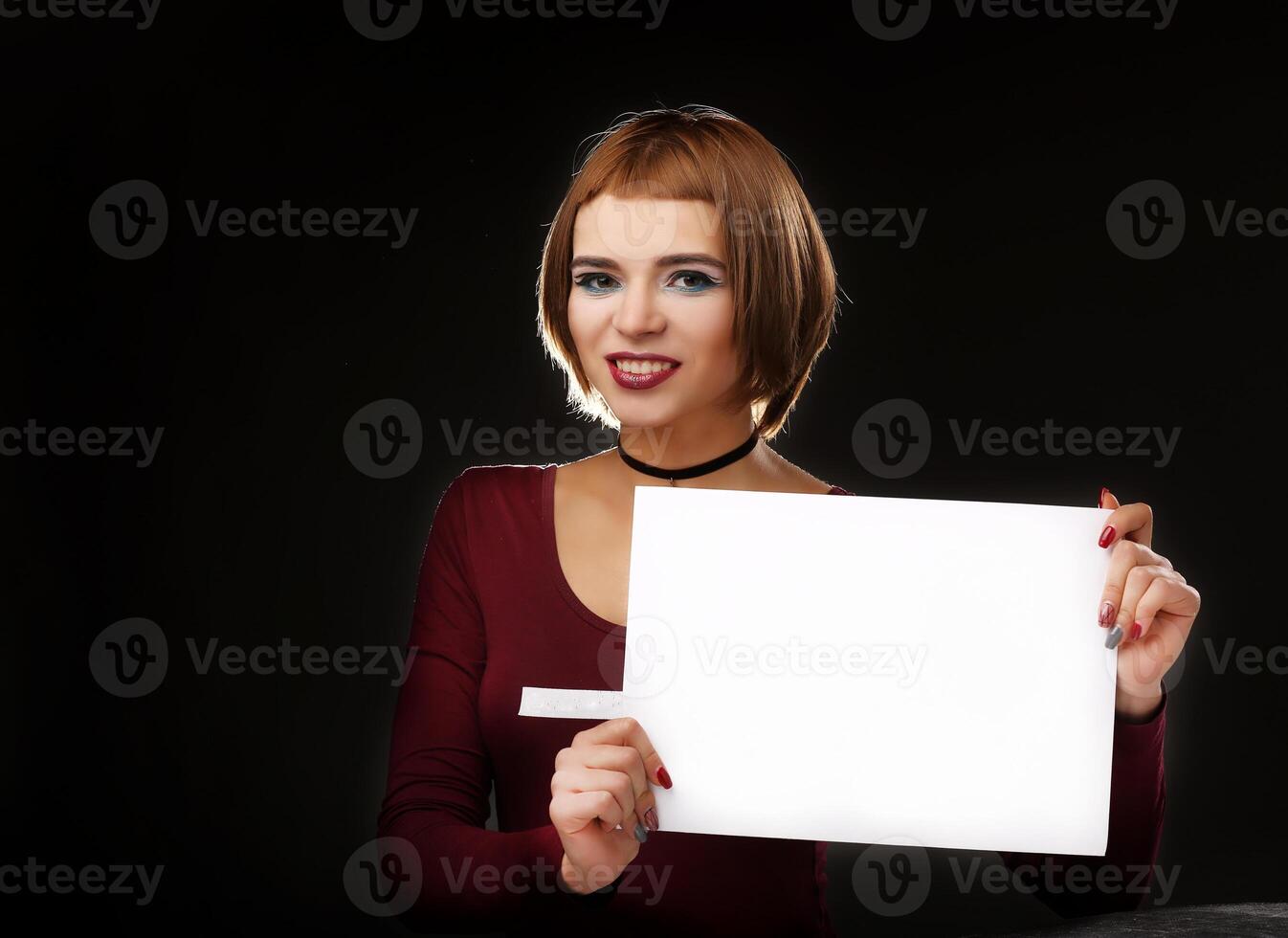Young beautiful woman with a clean white sheet of paper. Portrait on a white background. A place to write a text. photo