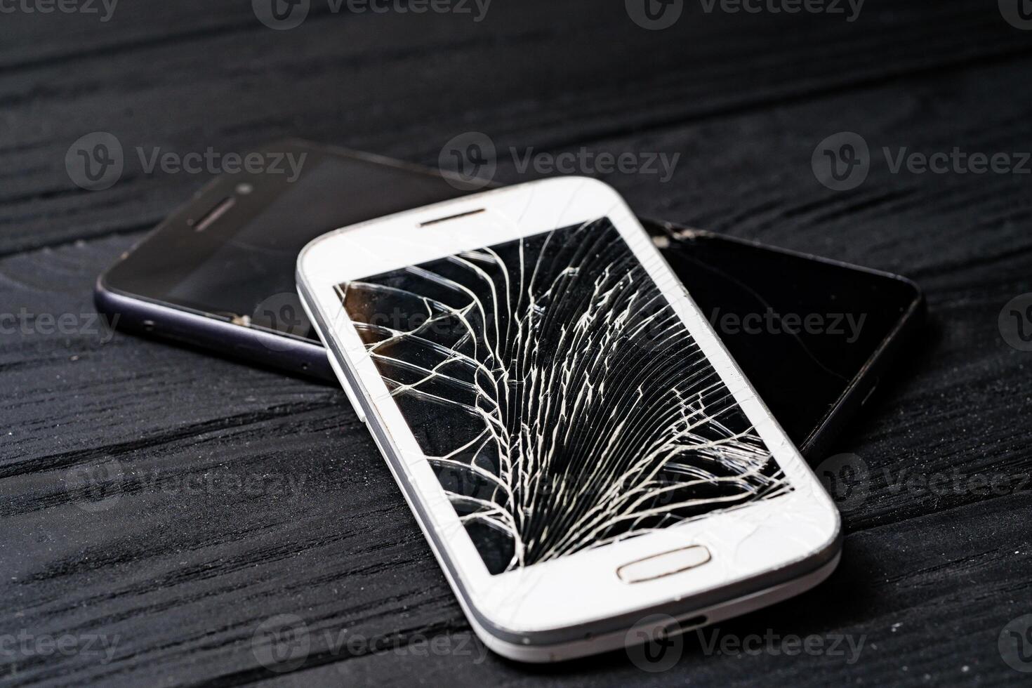 Smartphone with broken screen on dark background. Close-up. photo