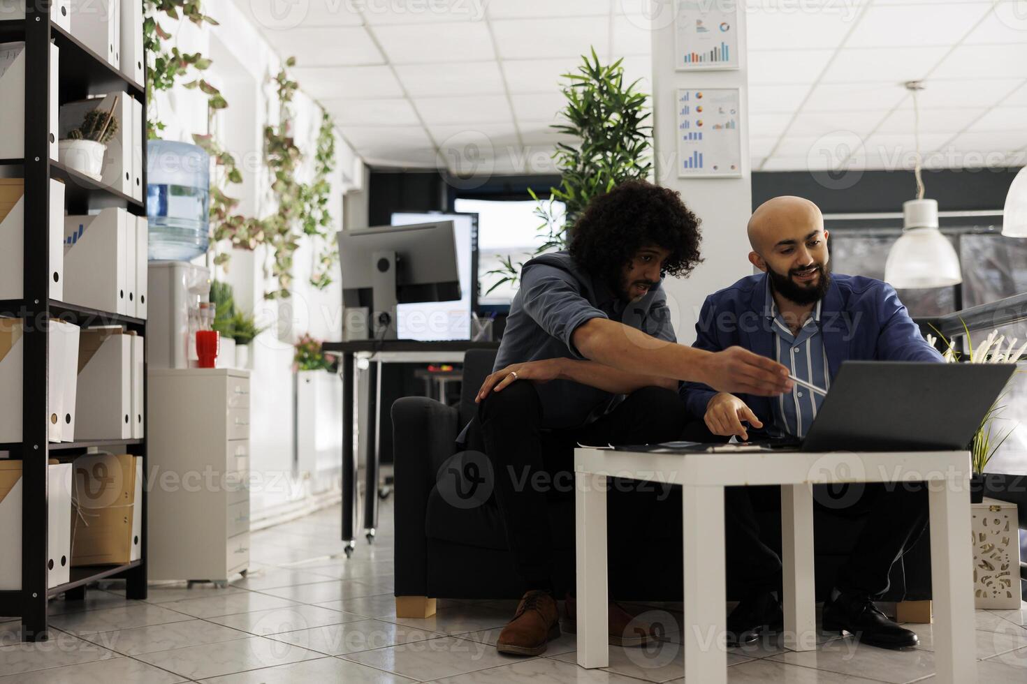 Two arab entrepreneurs reviewing financial analytics on laptop in unicorn business office. Executive manager and employee analyzing project progress in corporate coworking space photo
