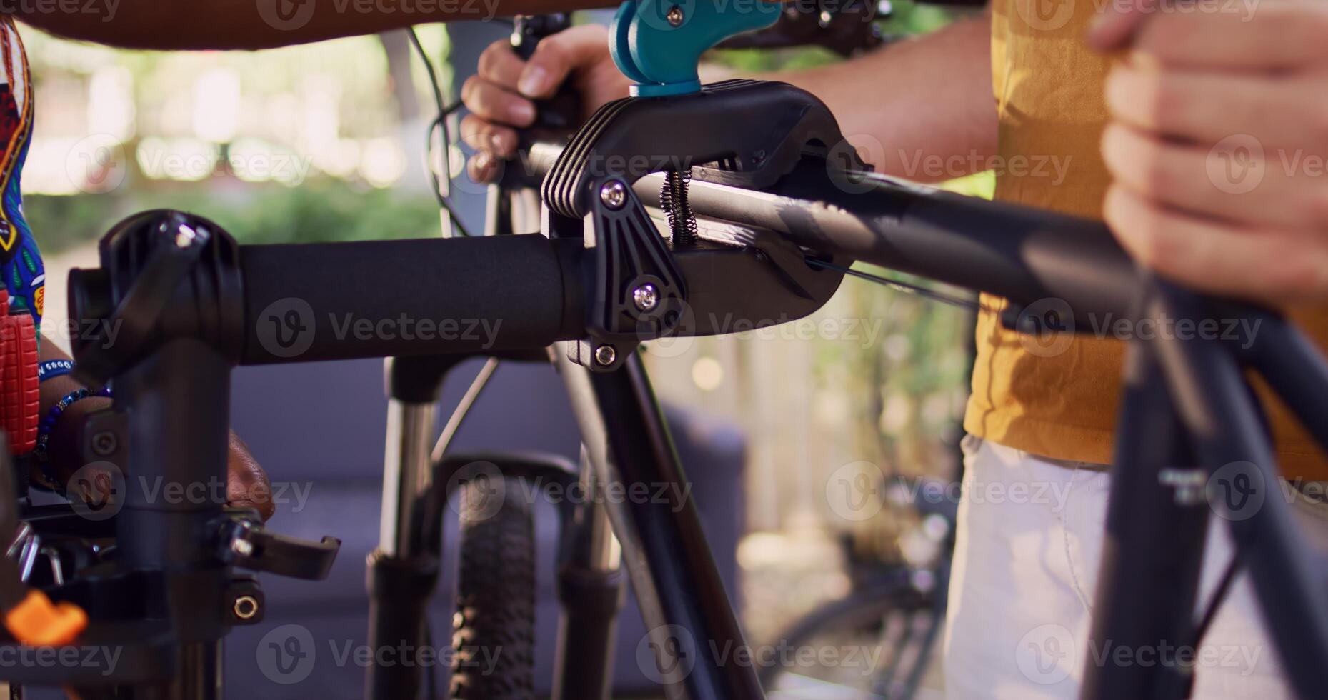 African american lady clamps the frame to repair-stand in this close-up of caucasian man carrying the bicycle. Multiracial couple fastening bike body for inspection and repair. photo