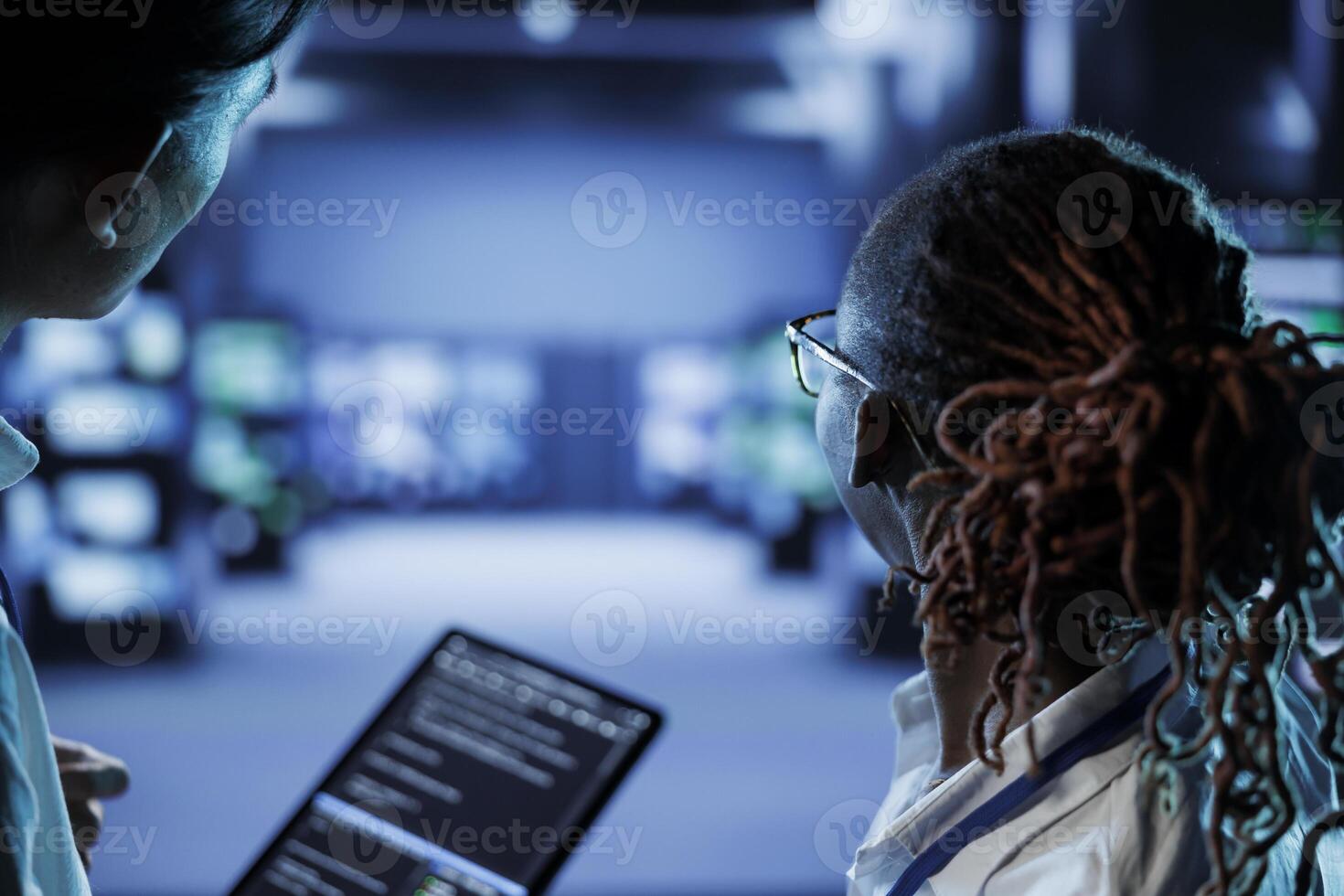 Team of engineers building firewall systems in server room housing advanced infrastructure. Capable employees running code on tablet to upgrade data center rigs handling demanding workloads photo
