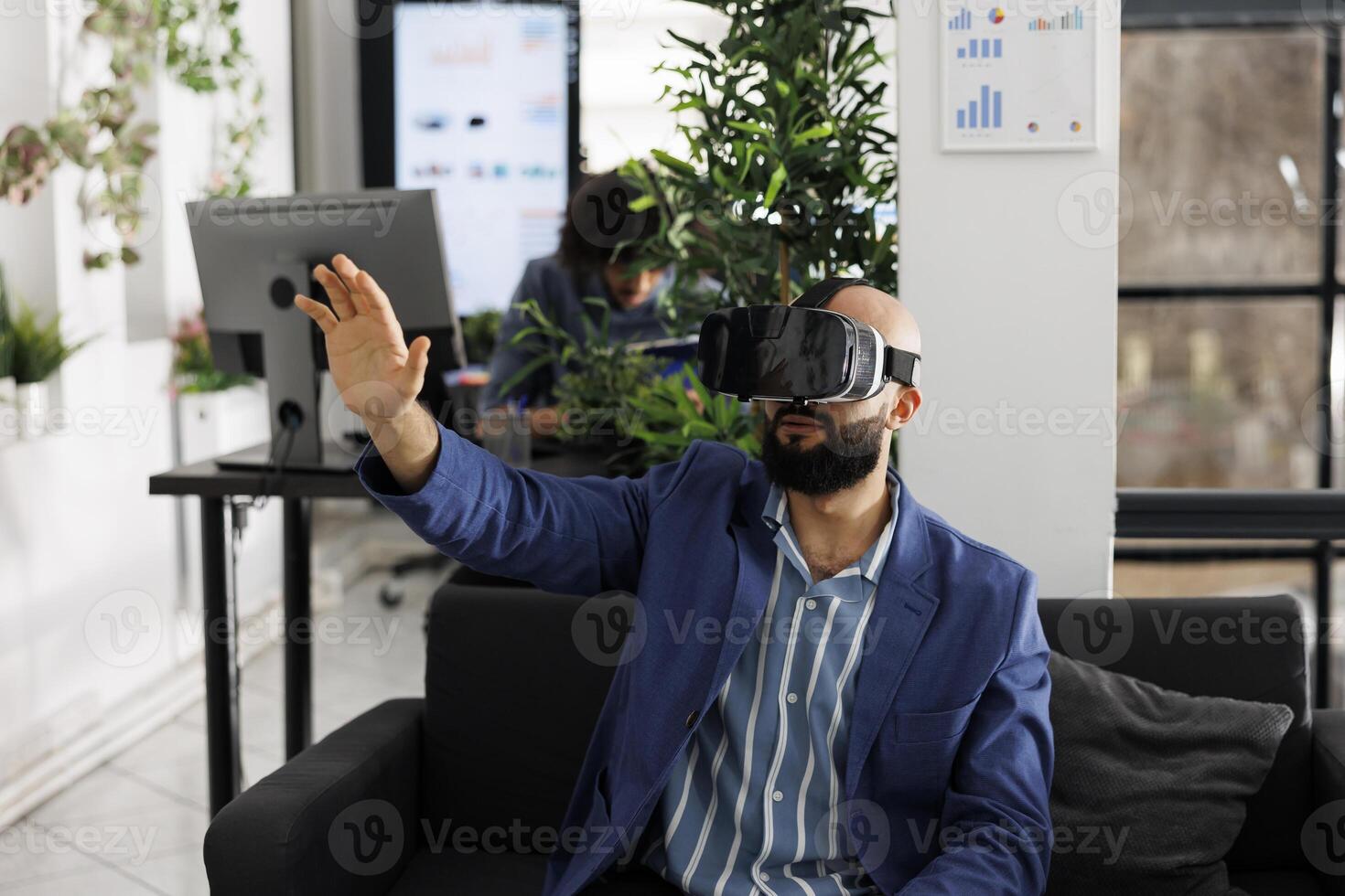 Entrepreneur using vr glasses for market research and analysis while working in business office. Project manager wearing virtual reality headset while sitting on couch in coworking space photo