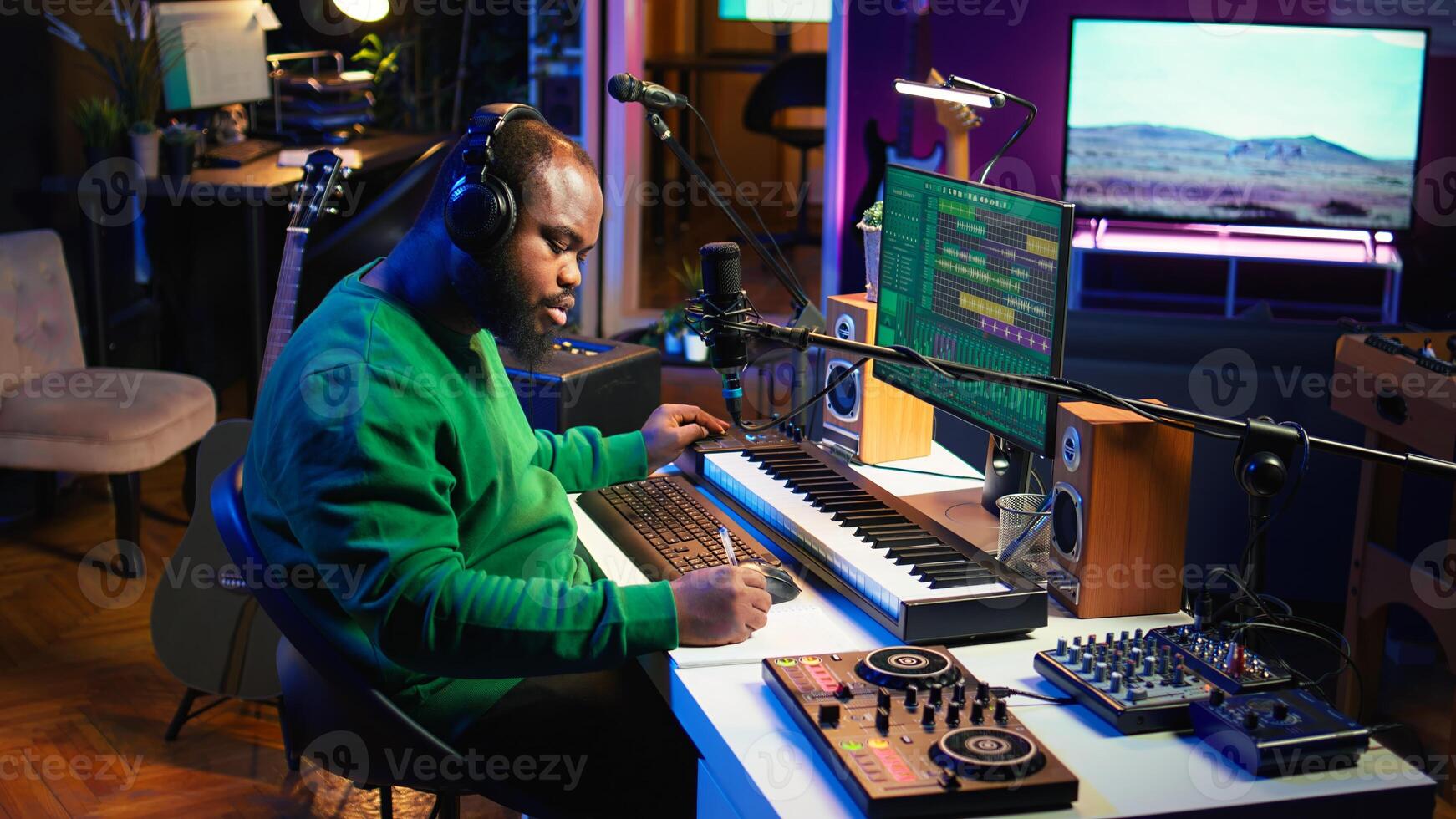 Talented famous composer writes down new verses and lyrics in home studio, composing music with digital software. Artist songwriter works with audio equipment and gear, recording tracks. Camera B. photo