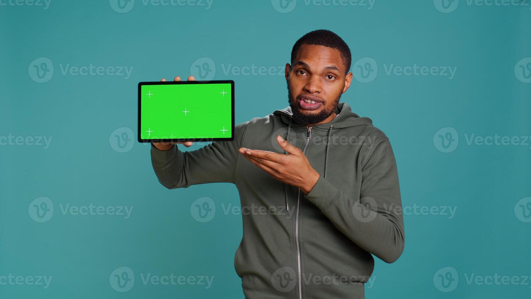 Tech content creator holding isolated screen tablet, doing promotion, talking with audience. Man pointing towards chroma key digital device, doing advertising, studio backdrop, camera B photo
