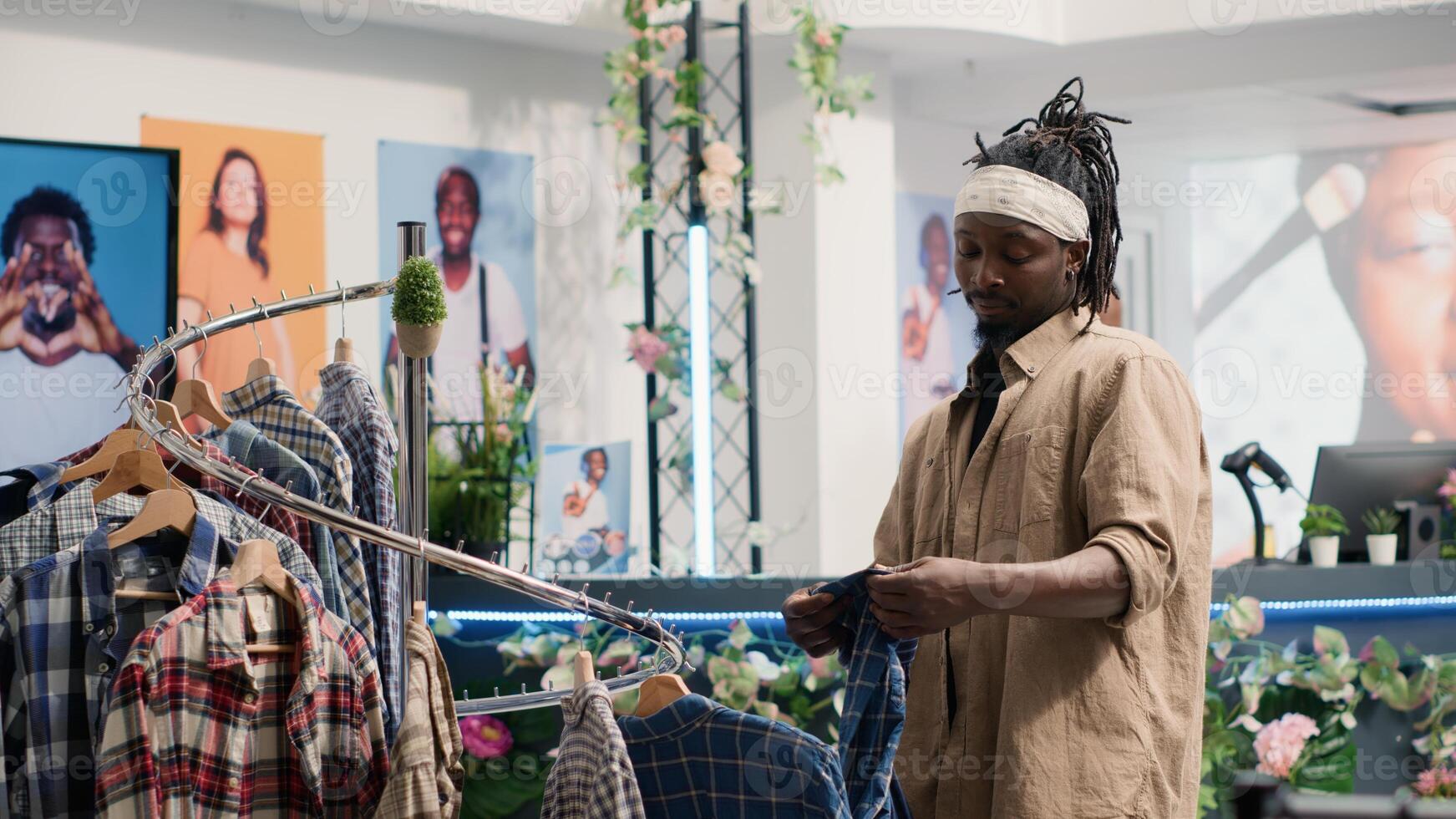 Man closely looking at shirts in clothing store, trying to determine if materials are qualitative. Customer analyzing garments in fashion boutique, looking to buy only top quality resistant apparel photo