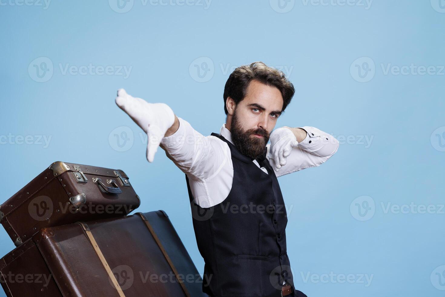 Trendy doorman dancing and having fun on camera, acting funny in professional attire. Hotel concierge worker being funky and silly fooling around next to trolley bags, happy bellman. photo