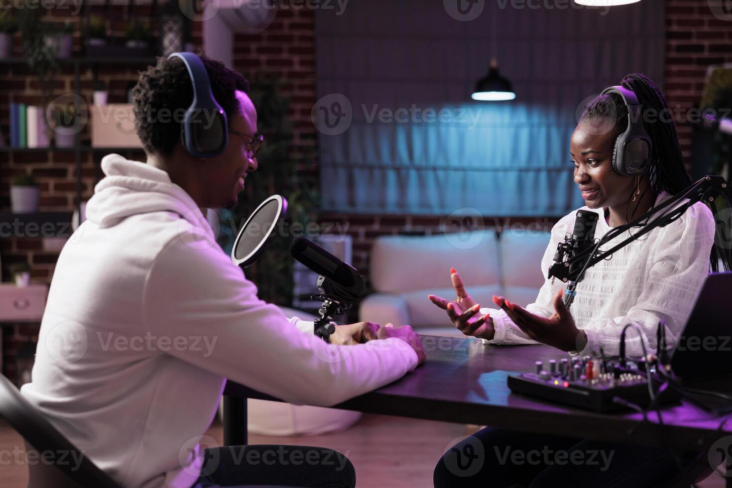 Online show host interviewing african american woman sharing financial advice during business focused podcast. Talking show interviewer using professional mic and decor to broadcast interview live photo