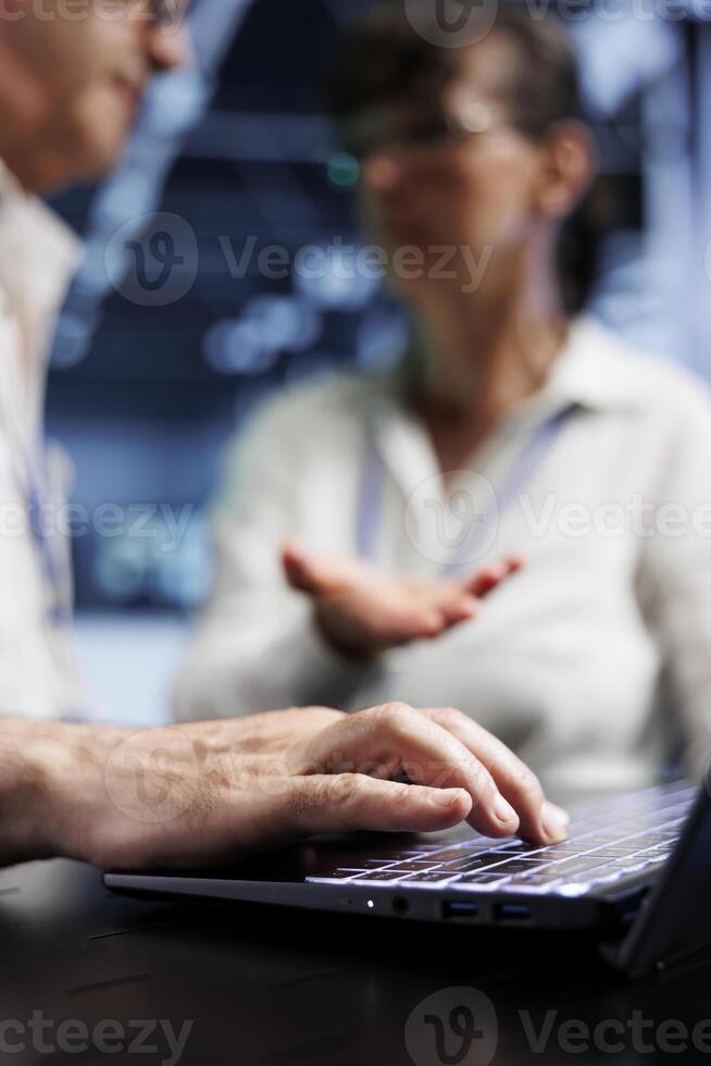Data storage company executives discussing how to prevent high tech facility hardware strains caused by AI applications driving up power usage. Technical support consultants fixing racks, close up photo