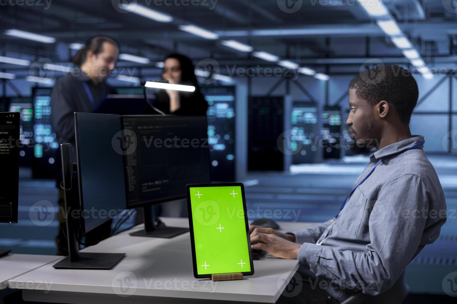 Technician works on green screen tablet in data center housing storage equipment. Man using chroma key device in server room with networking components providing vast amounts of computing resources photo