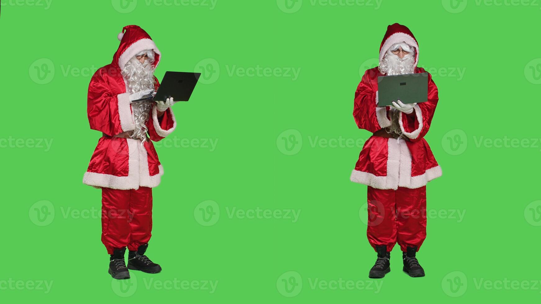 Santa claus cosplay works with laptop over greenscreen full body backdrop, using online browser in studio. Father christmas searching internet site while he is dressed with costume and hat. photo