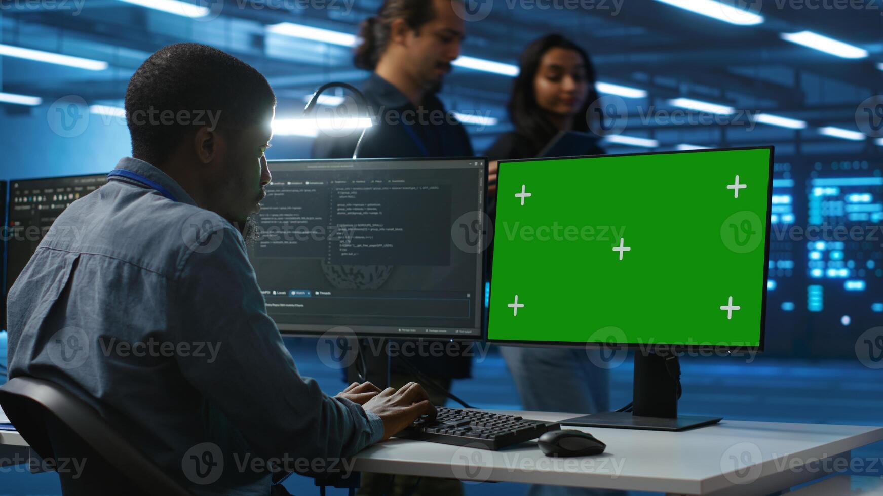IT technician looking at green screen PC, working in data center, ensuring optimal performance. Man monitoring energy consumption across operational server rigs components using chroma key monitor photo