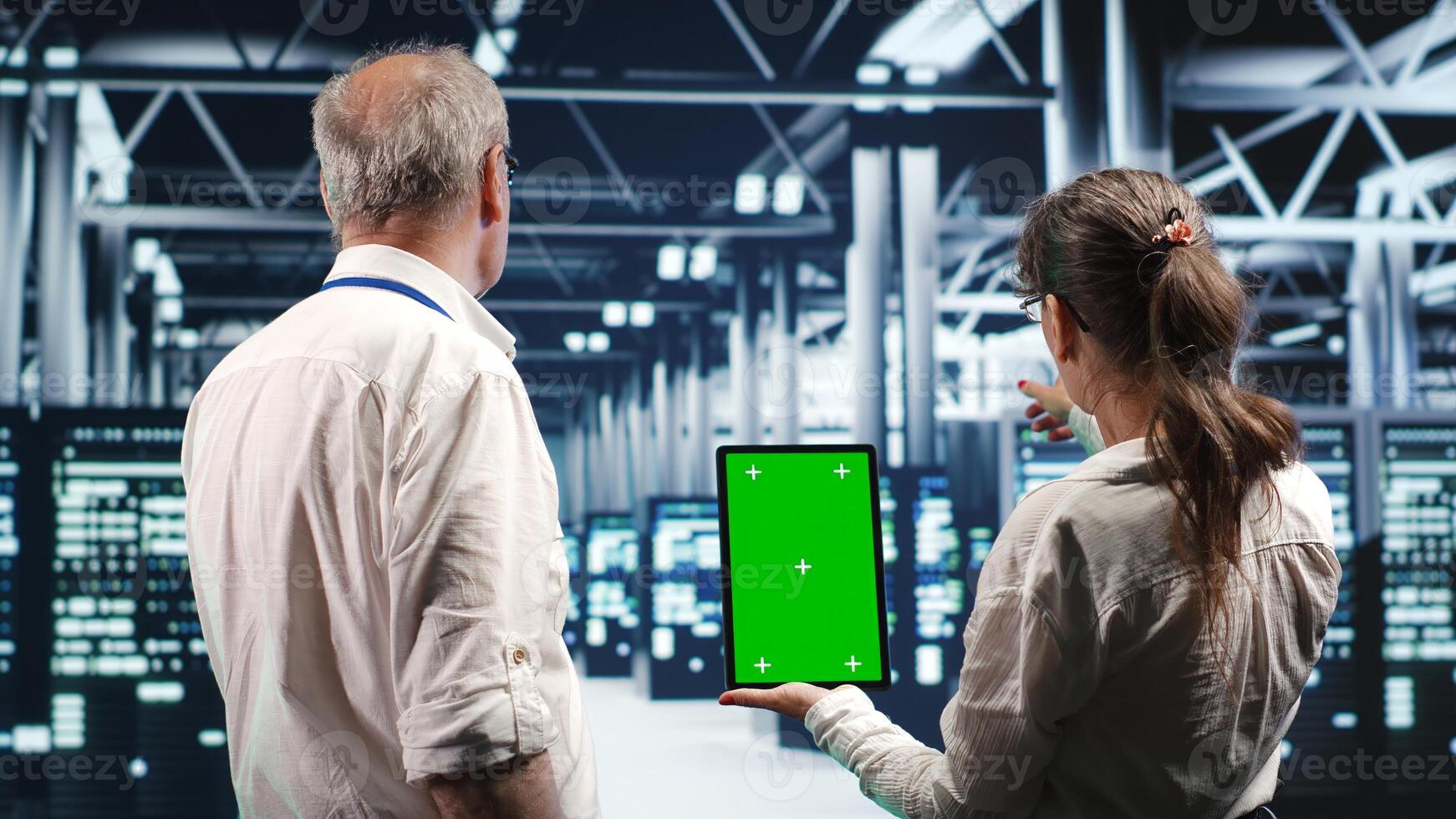 Experts using chroma key tablet to monitor energy efficient data center clusters. Server devices using renewable sources employed to minimize consumption and reduce overall workspace carbon footprint photo