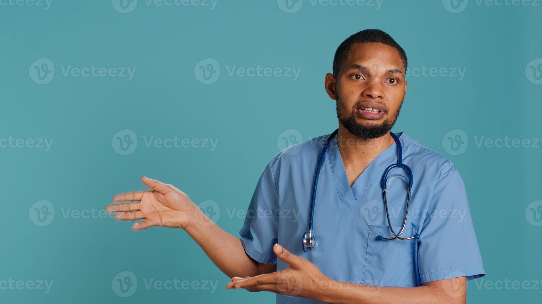 Portrait of african american nurse pointing hands towards empty space, doing advertising, talking with audience. Healthcare employee doing promotional ad, showing copy text, studio backdrop, camera A photo