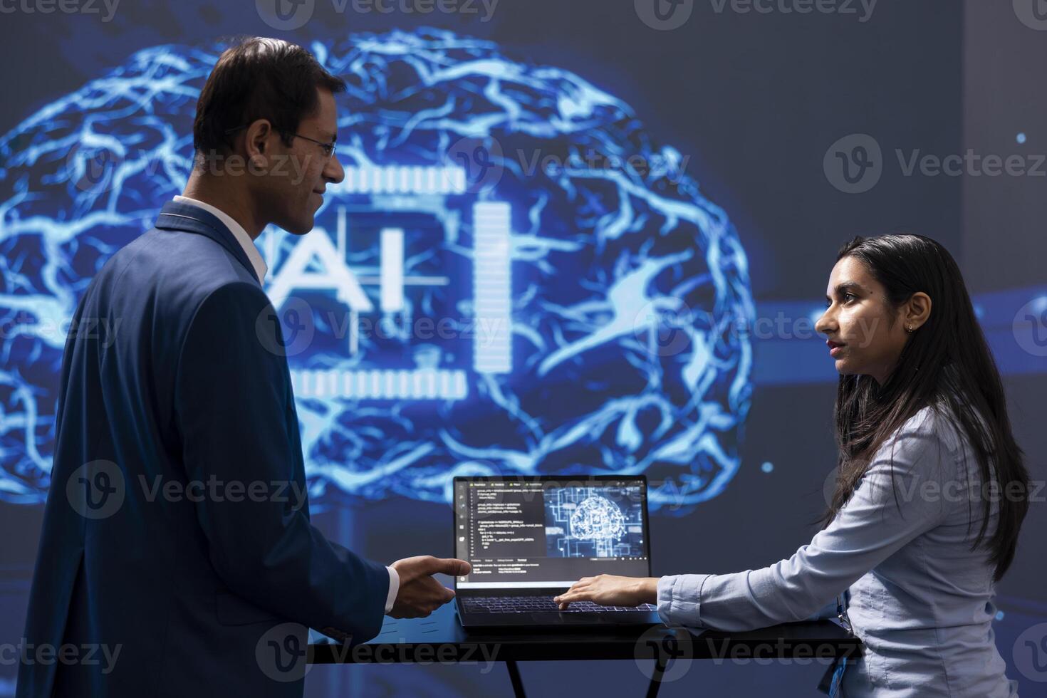 IT staff members solving tasks on laptop device, running artificial intelligence programming scripts. Indian workers using notebook to write lines of code for AI applications development photo