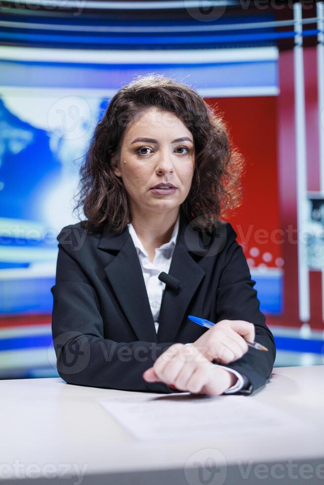 Newscaster talking about latest events on live broadcast transmission, presenting daily happenings and celebrity gossips. News anchor woman covering all headlines and topics in studio. photo